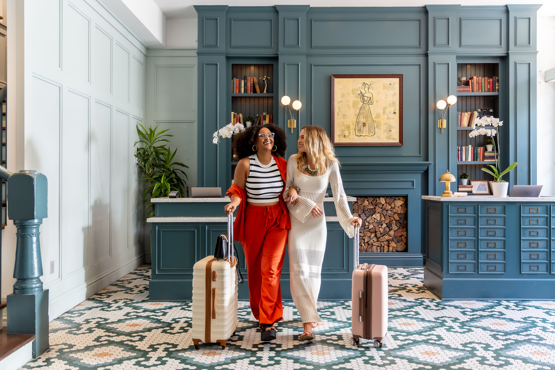 commercial photo of two women walking in a hotel lobby with suitcases
