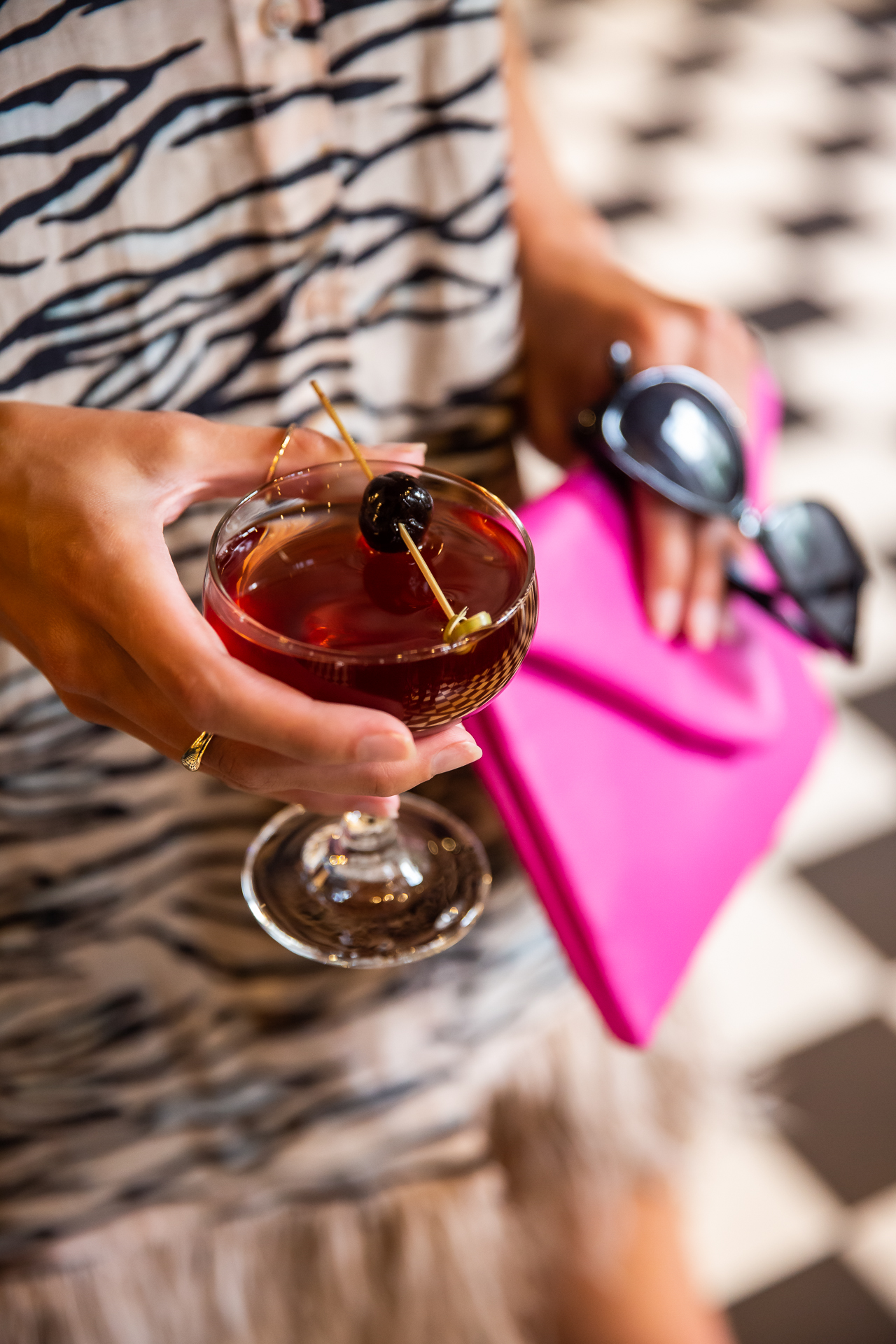 commercial photography of a woman holding a cocktail and purse