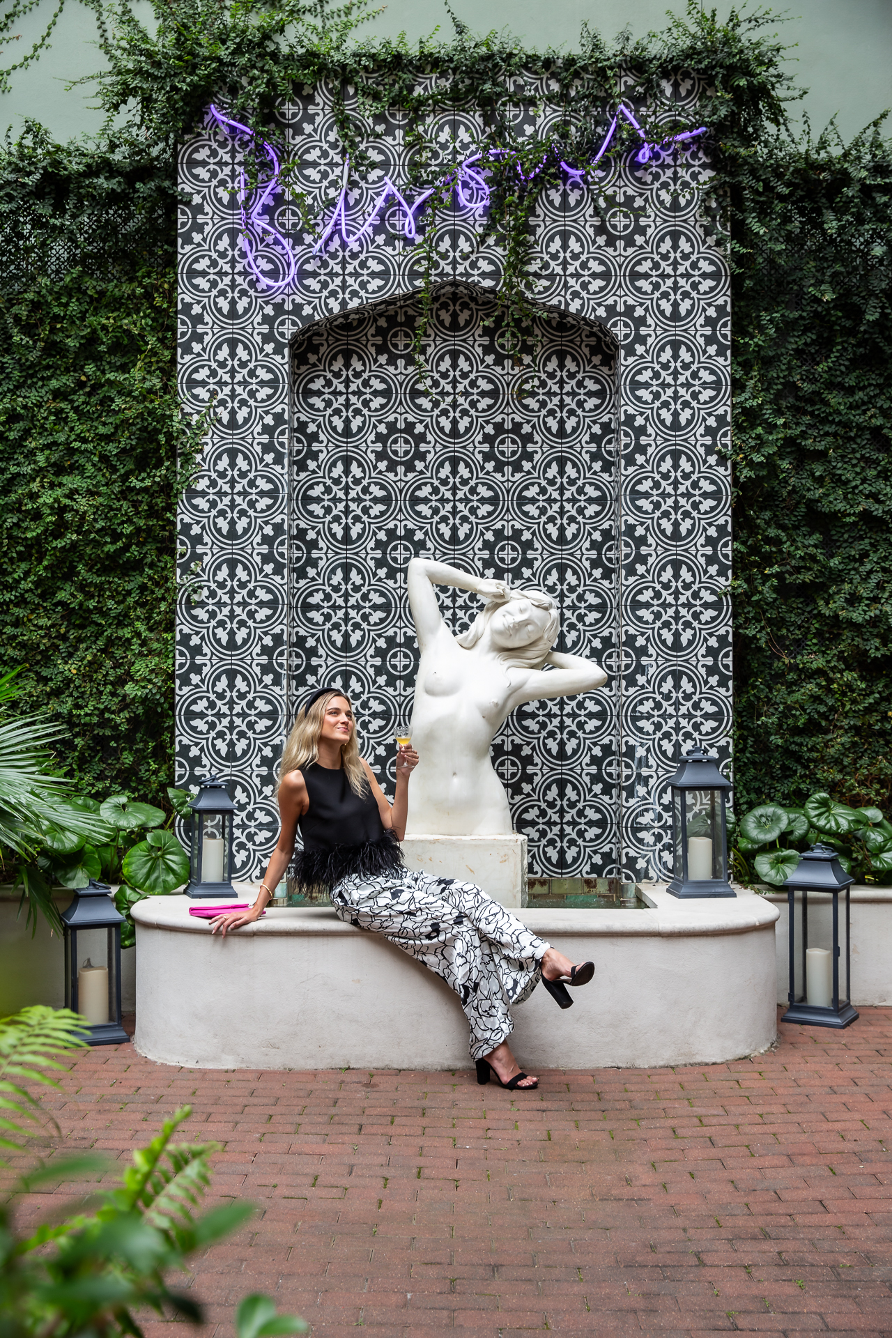a woman sitting next to a fountain at the eliza jane hotel in new orleans