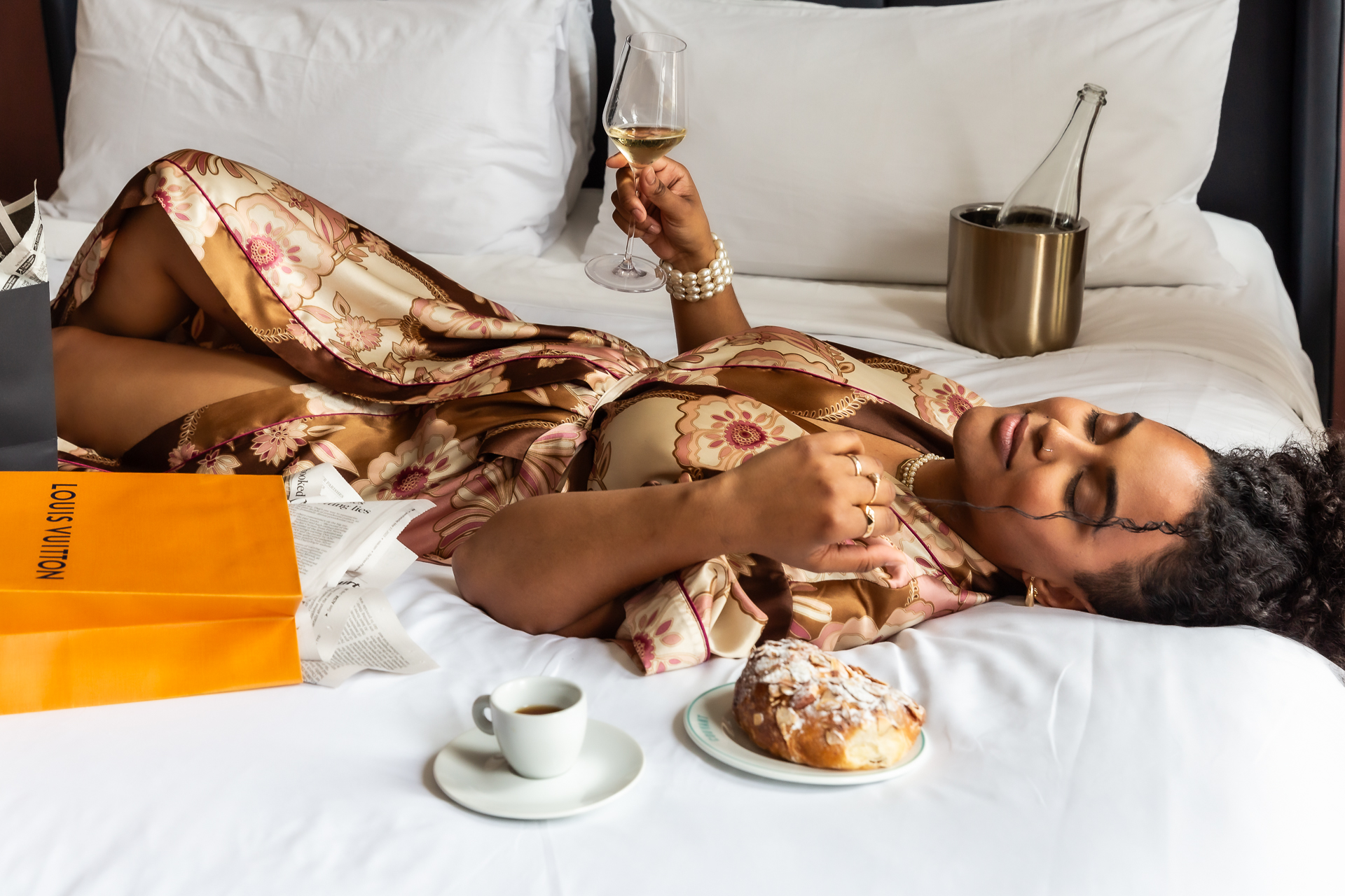 commercial photo of woman relaxing on a bed with wine and coffee
