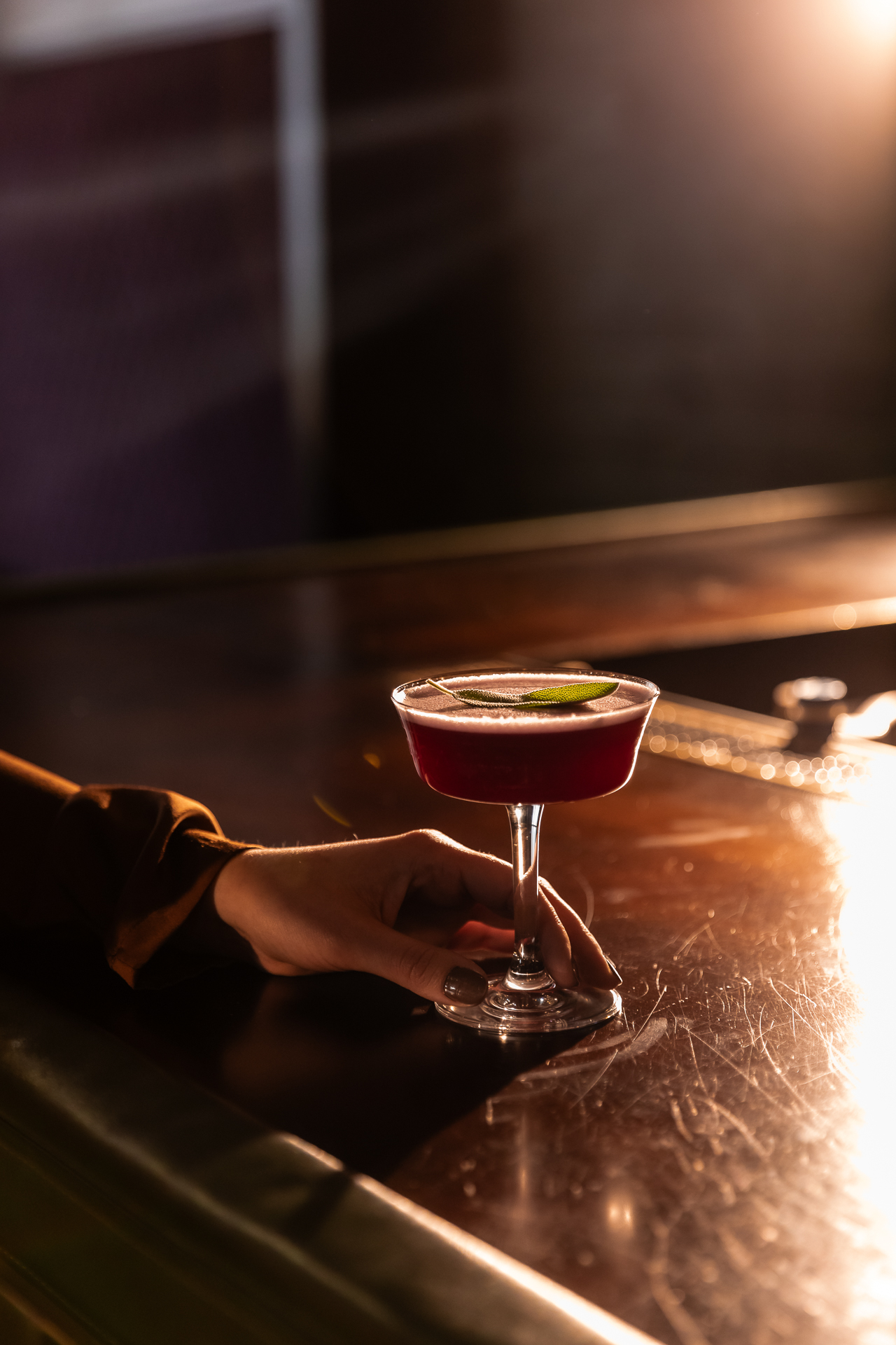 commercial photography at 21C museum hotel of a cocktail on the bar with woman's hand