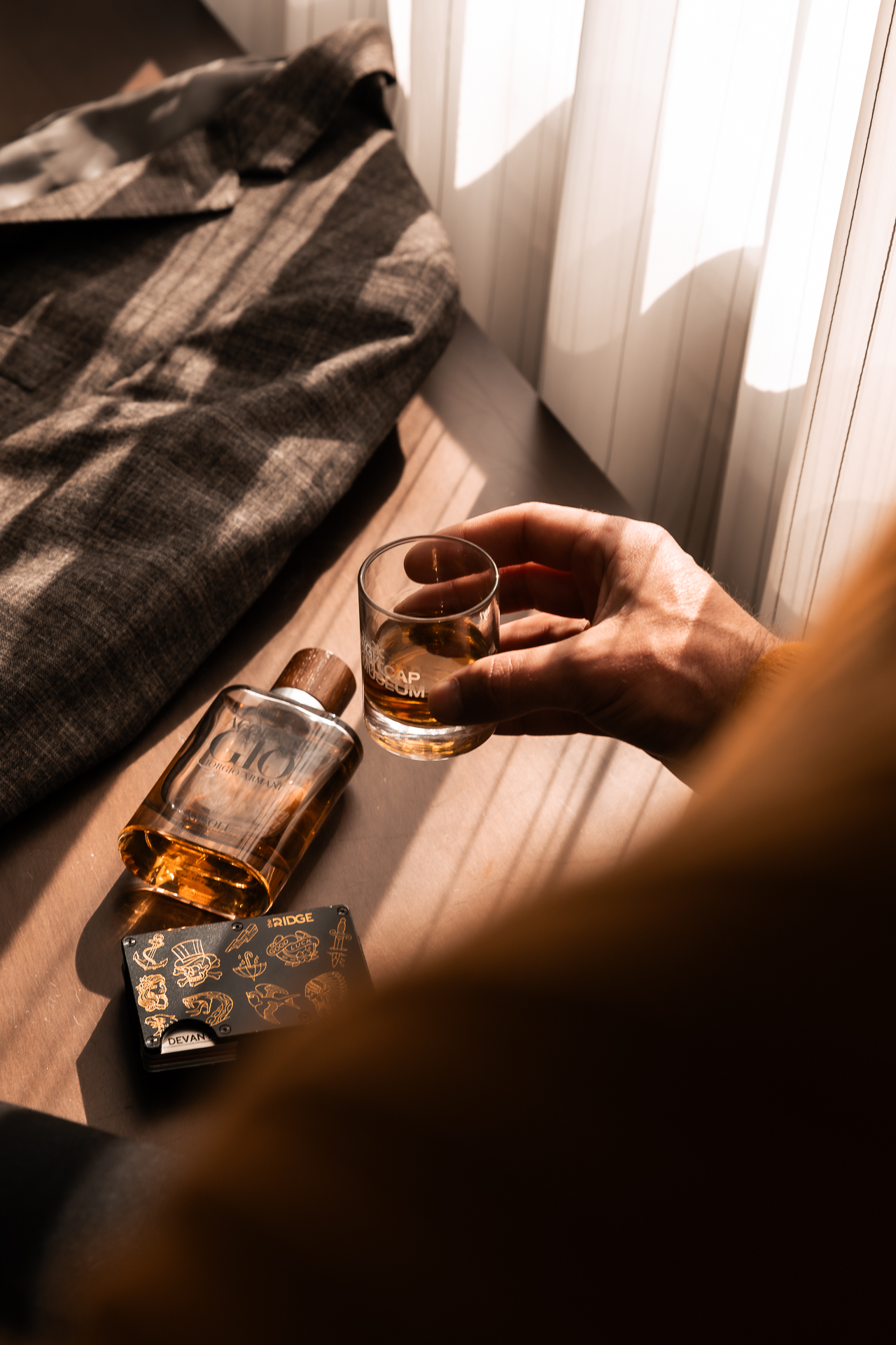 commercial photography at 21C museum hotel of sunlight streaming over accessories and a small glass of whiskey