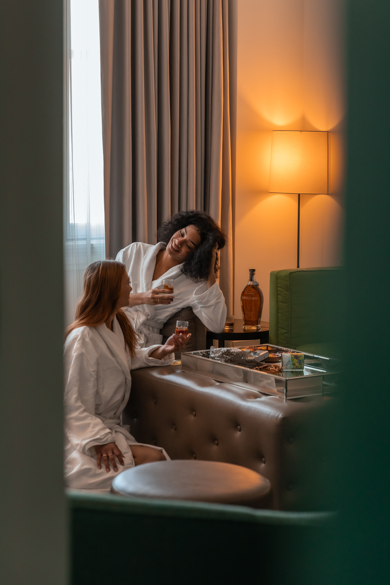 commercial photography at 21C museum hotel of two women in their hotel room lounge, sitting on the floor near a table with drinks