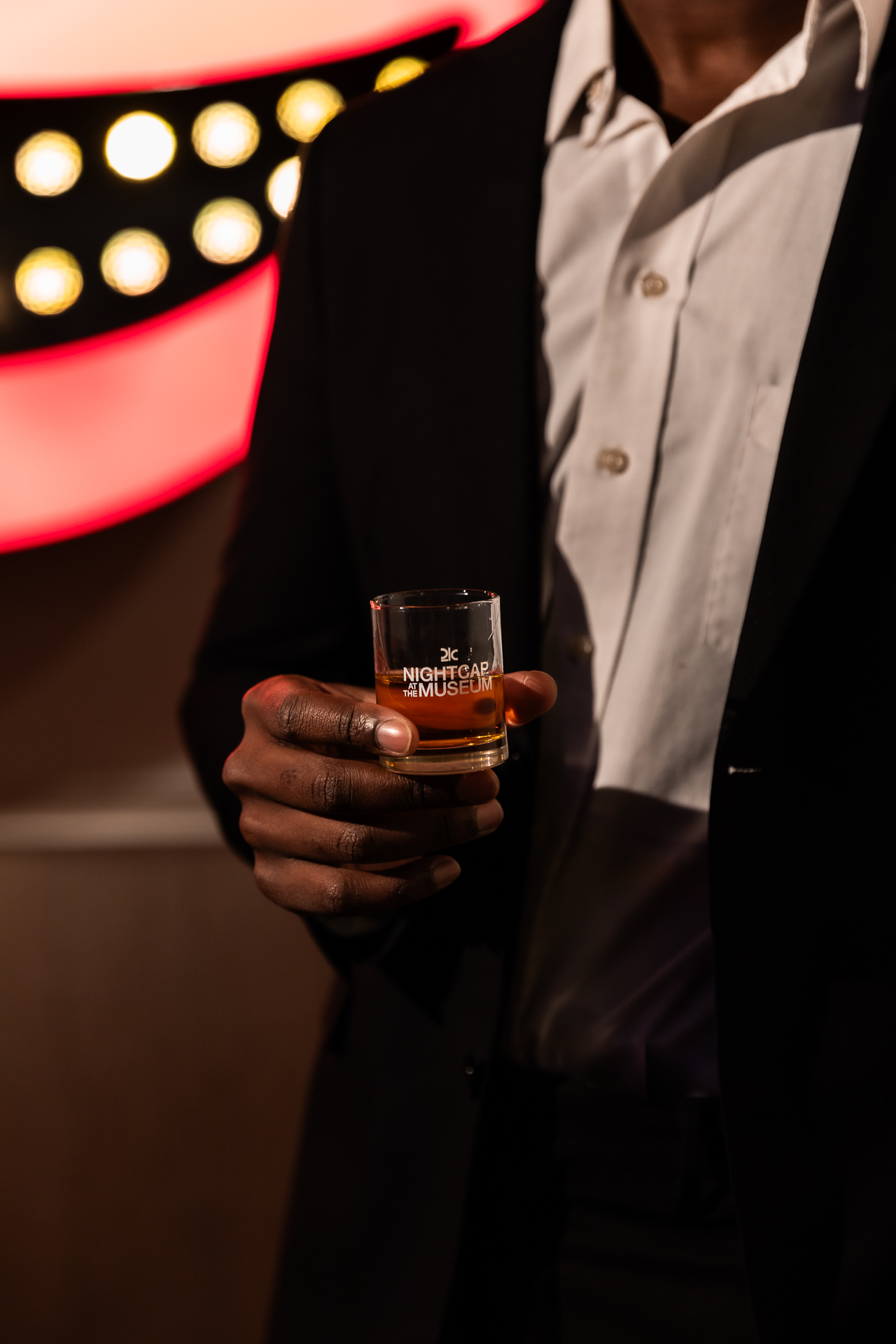 commercial photography at 21C museum hotel of a man holding a drink in front of neon lights