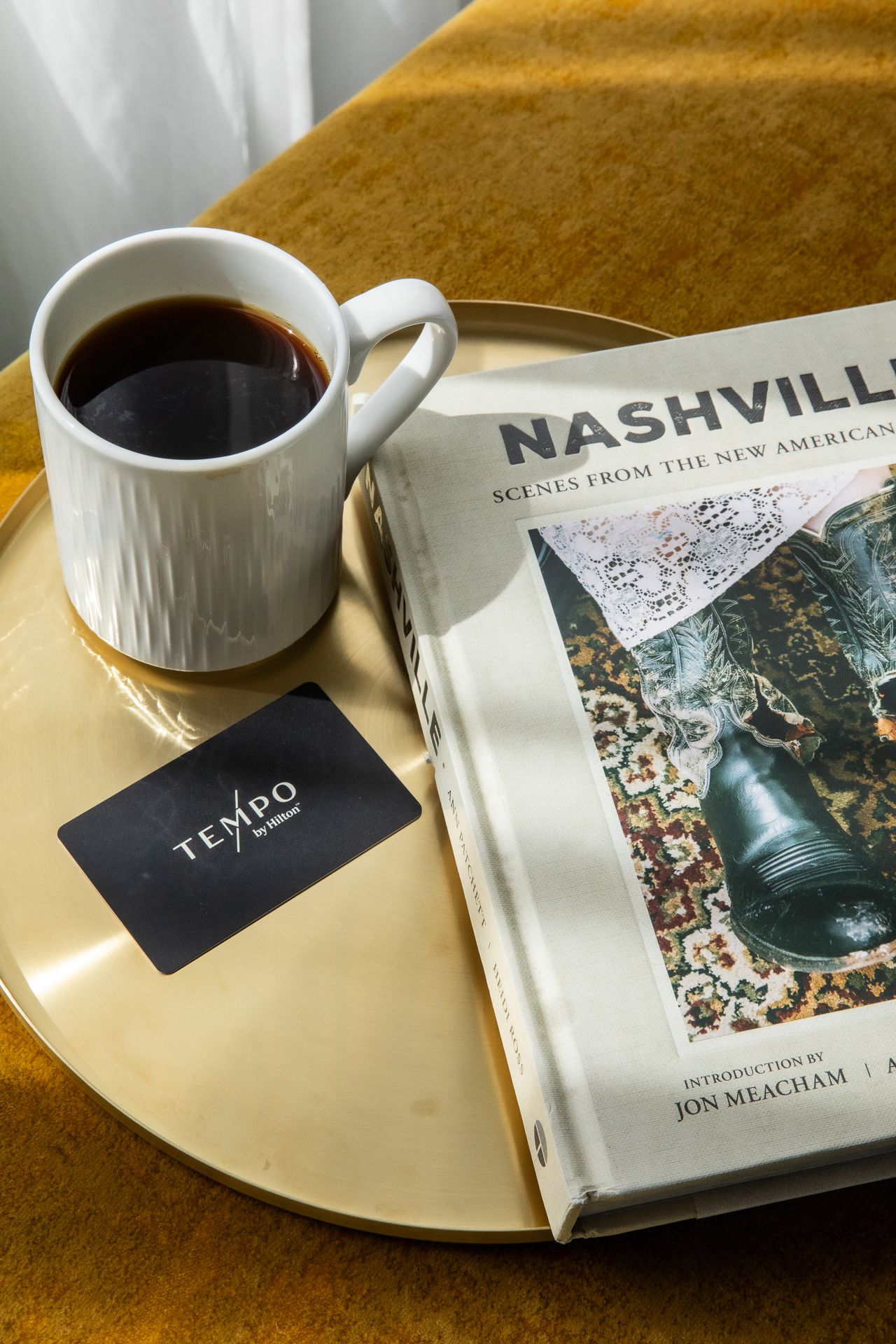 commercial photography of a hotel room key at Tempo Nashville with coffee and a book