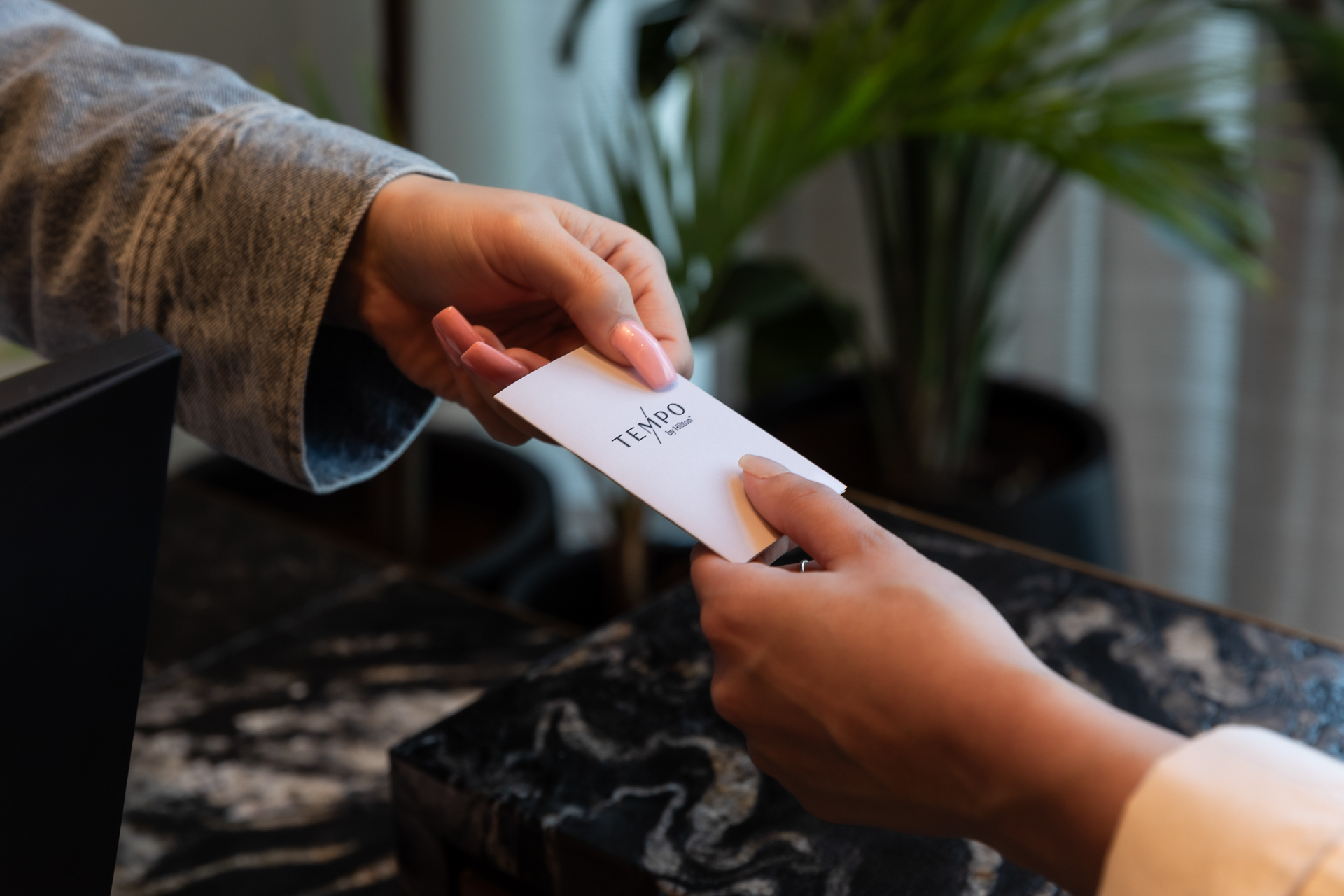 commercial photography of a room key at Tempo Nashville being handed to a guest by the receptionist