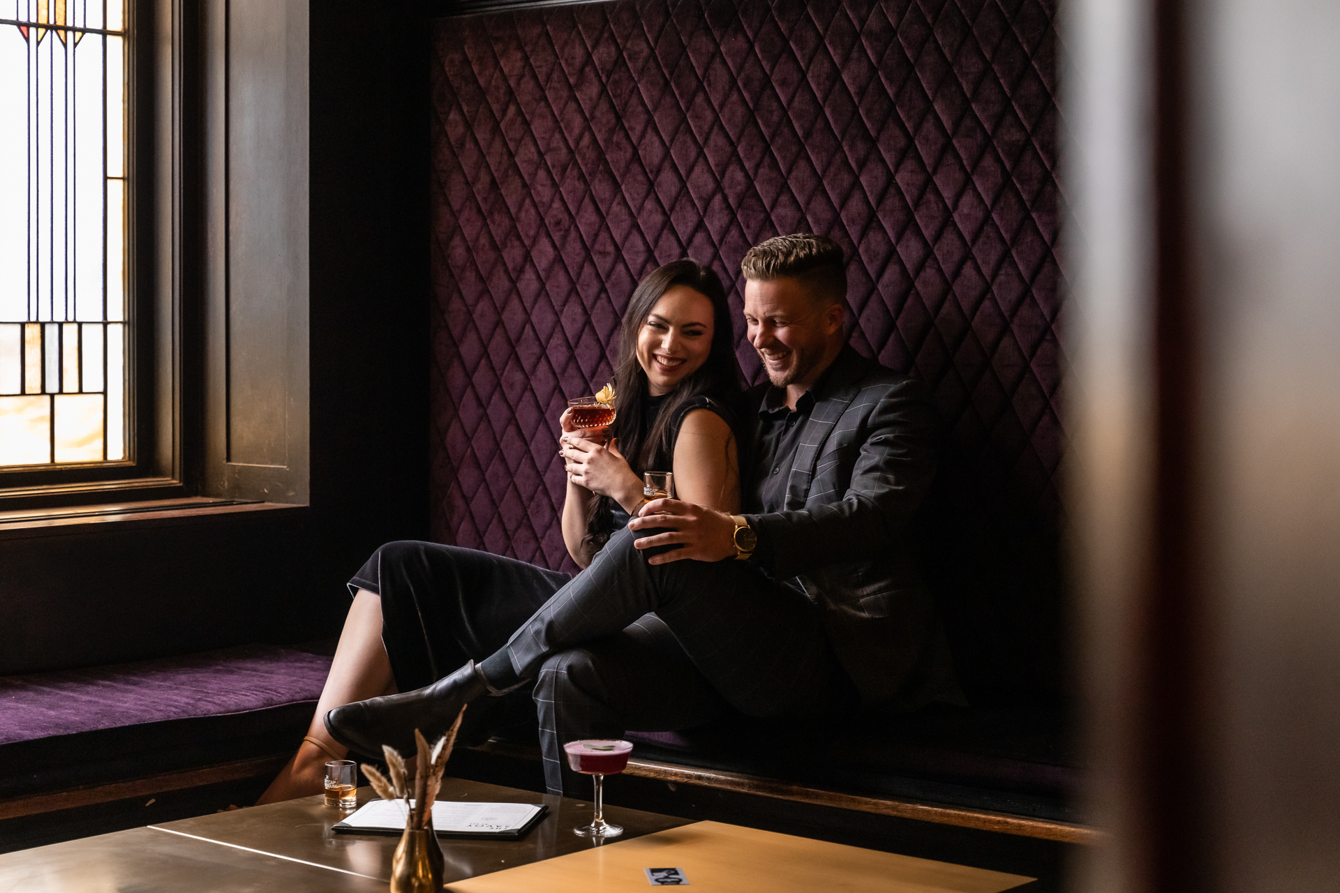 commercial photography at 21C museum hotel of a couple sitting in a purple velvet booth with drinks