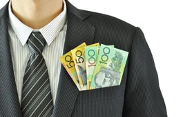 A man wearing a suit and tie with money in his pocket.