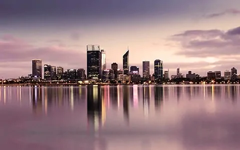 A city skyline is reflected in the water.