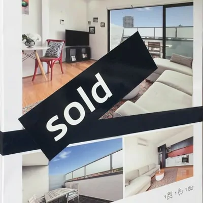 A real estate sold sign on a for sale board