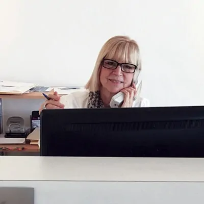 A woman sitting at a desk talking on a cell phone.