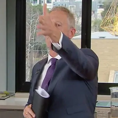 A man in a suit and tie standing in front of a window.