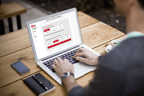 A man sitting at a table using a laptop computer.
