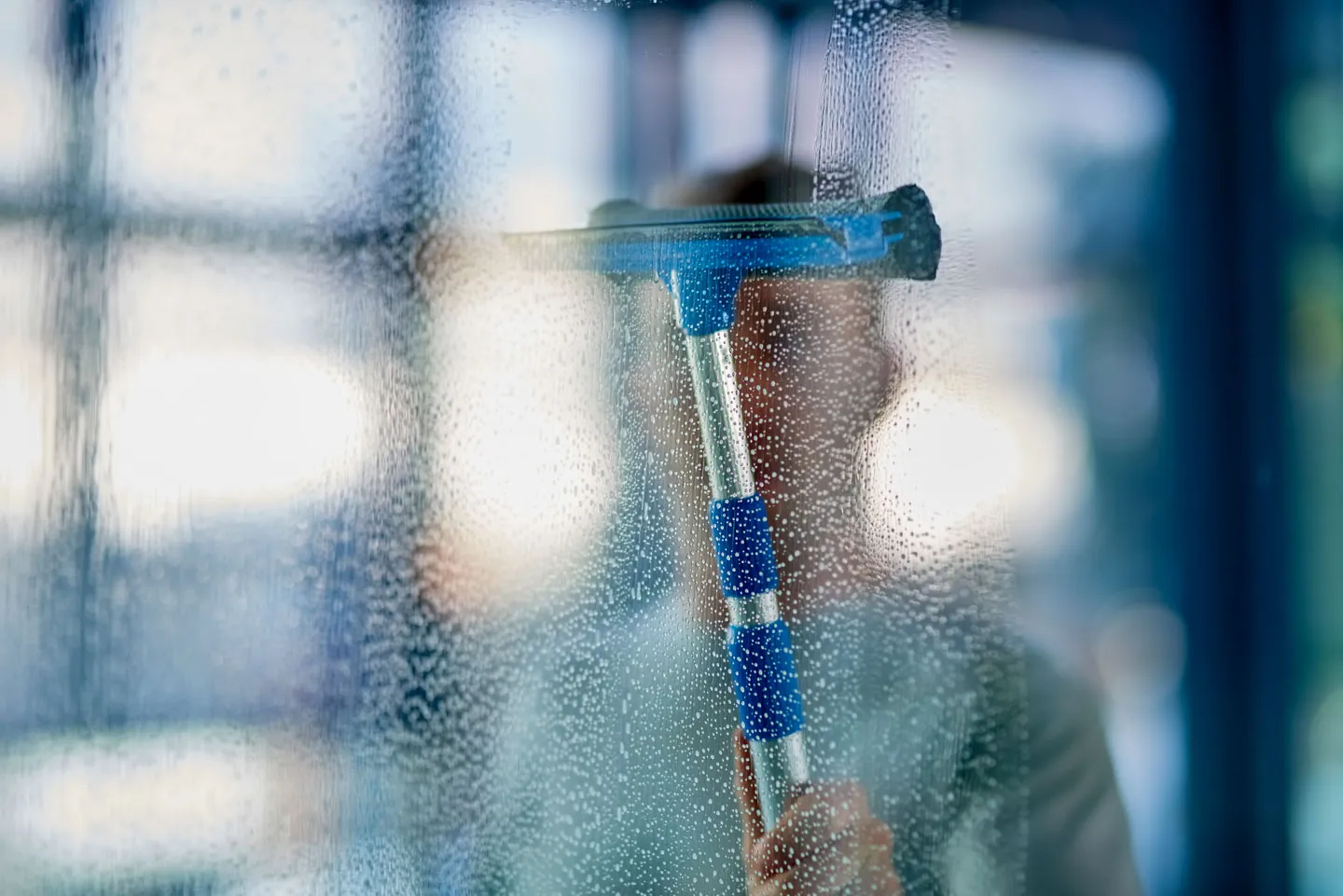 Reinigungsmitarbeiter reinigt Fenster