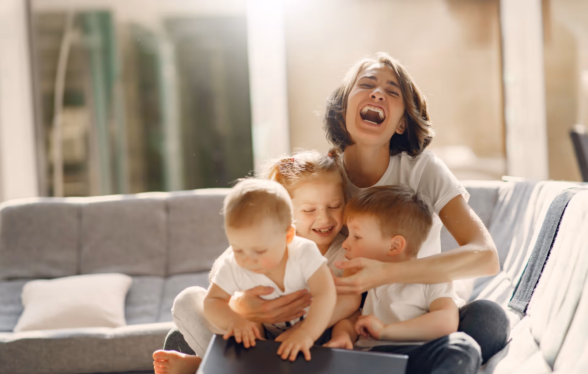 A woman sitting on top of a couch with three babies.