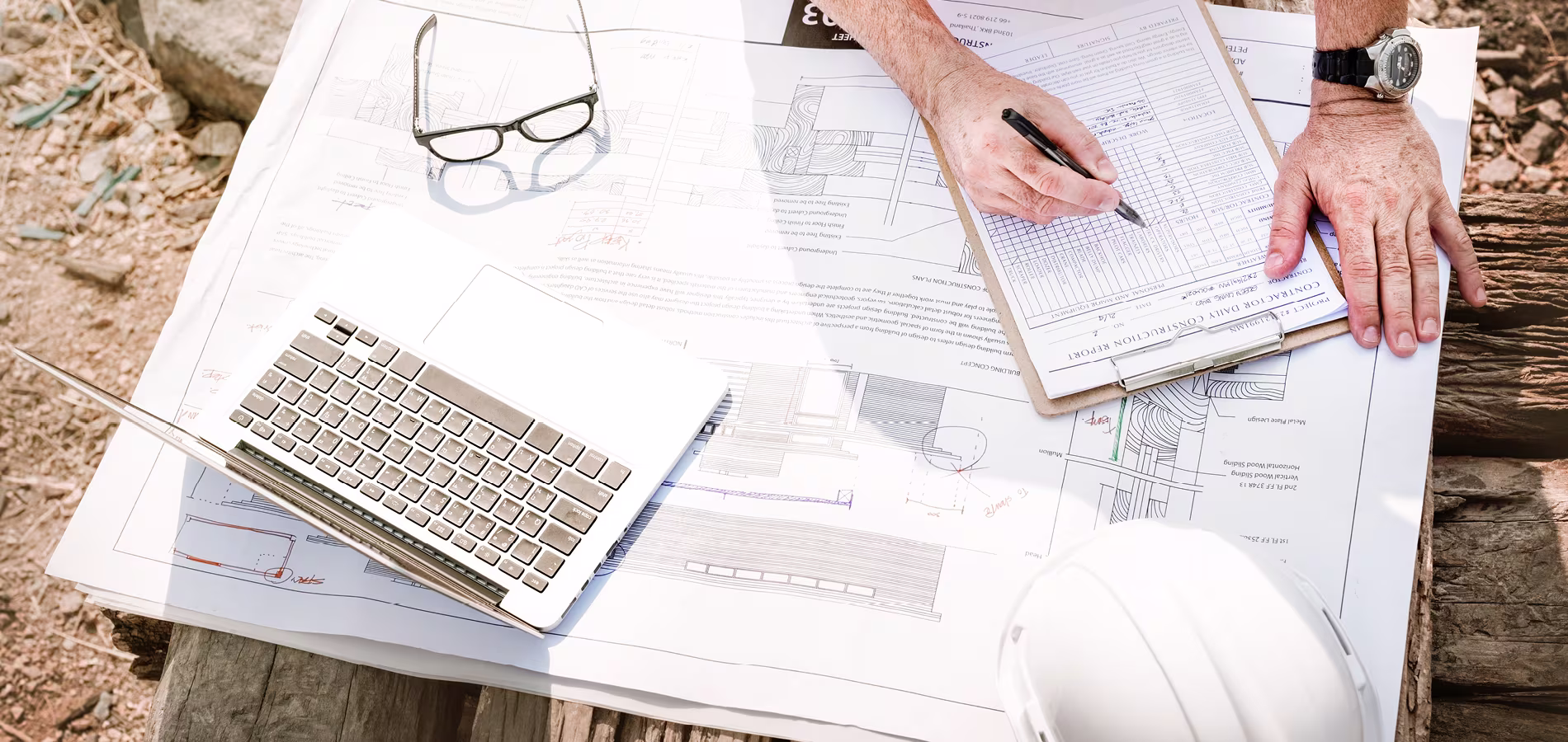 contractor-on-site-checking-floor-plans-inspection-checklist-and-permits-with-laptop-and-hard-hat