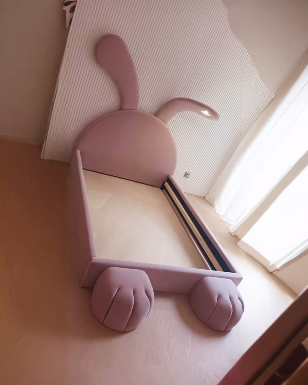 Dječji krevet u obliku zeca s ružičastim tapeciranjem.