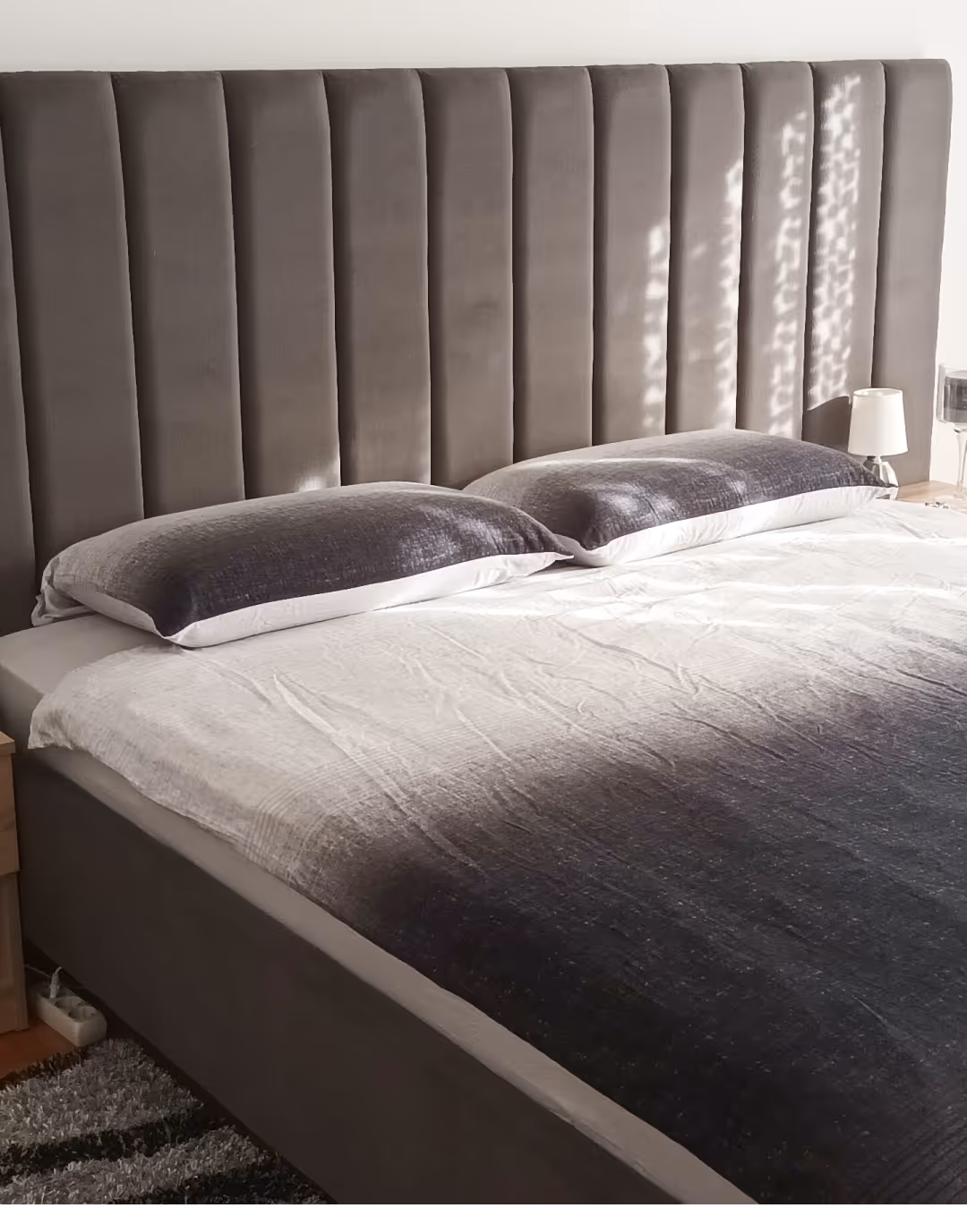Siva postelja s modernim tapeciranim uzglavljem
