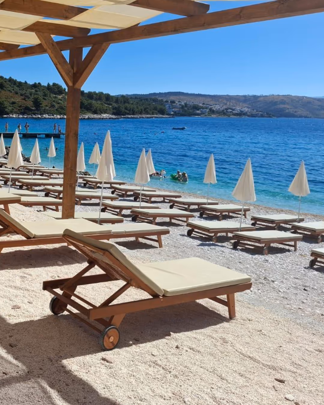 Ležaljke i suncobrani na šljunčanoj plaži uz Jadransko more.