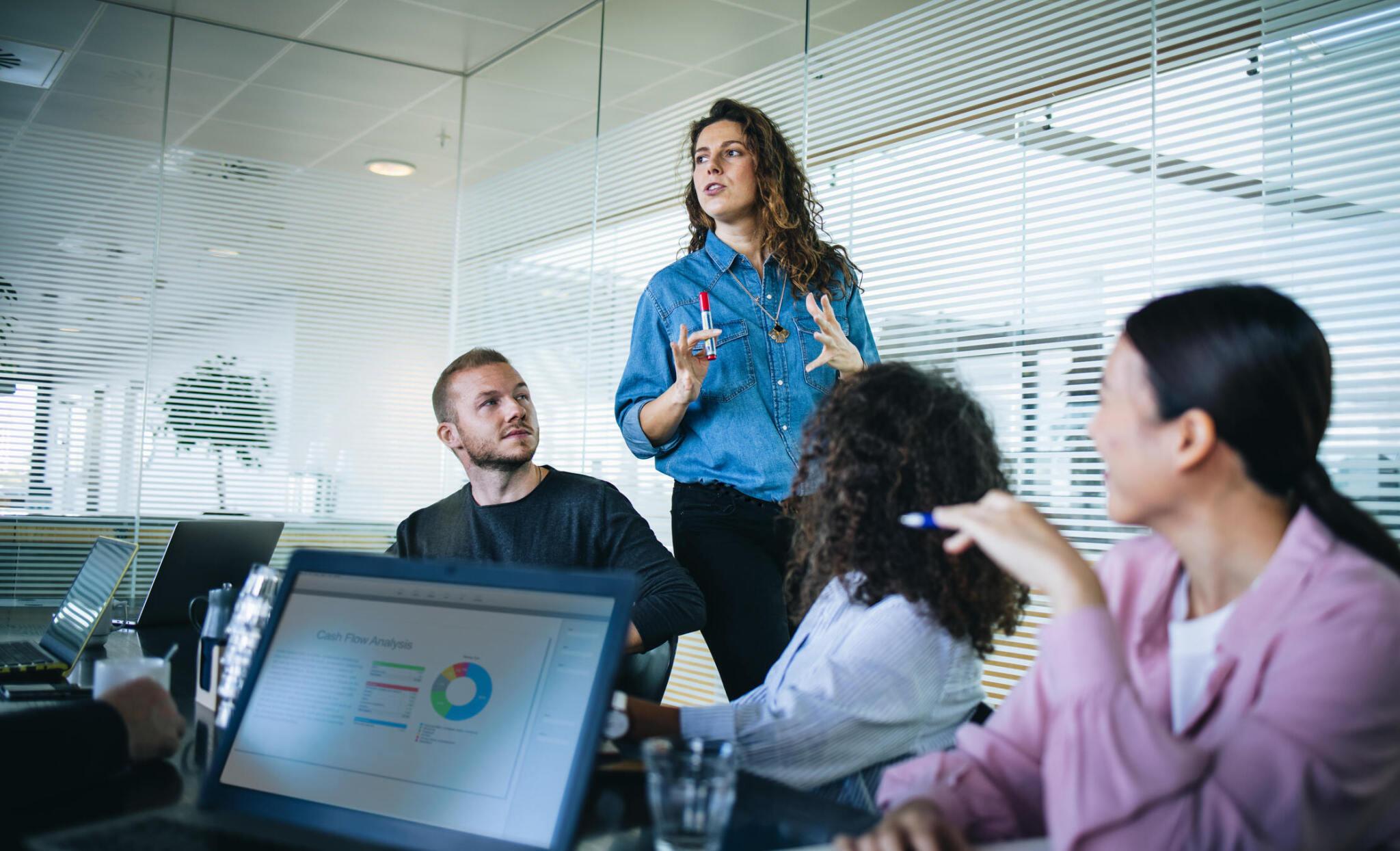 A woman presenting to colleagues in a modern office.
