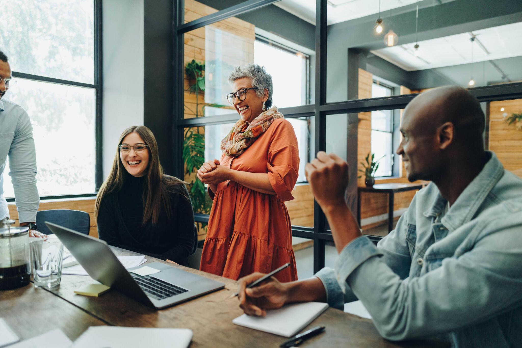 A woman presenting ideas to colleagues around a laptop.