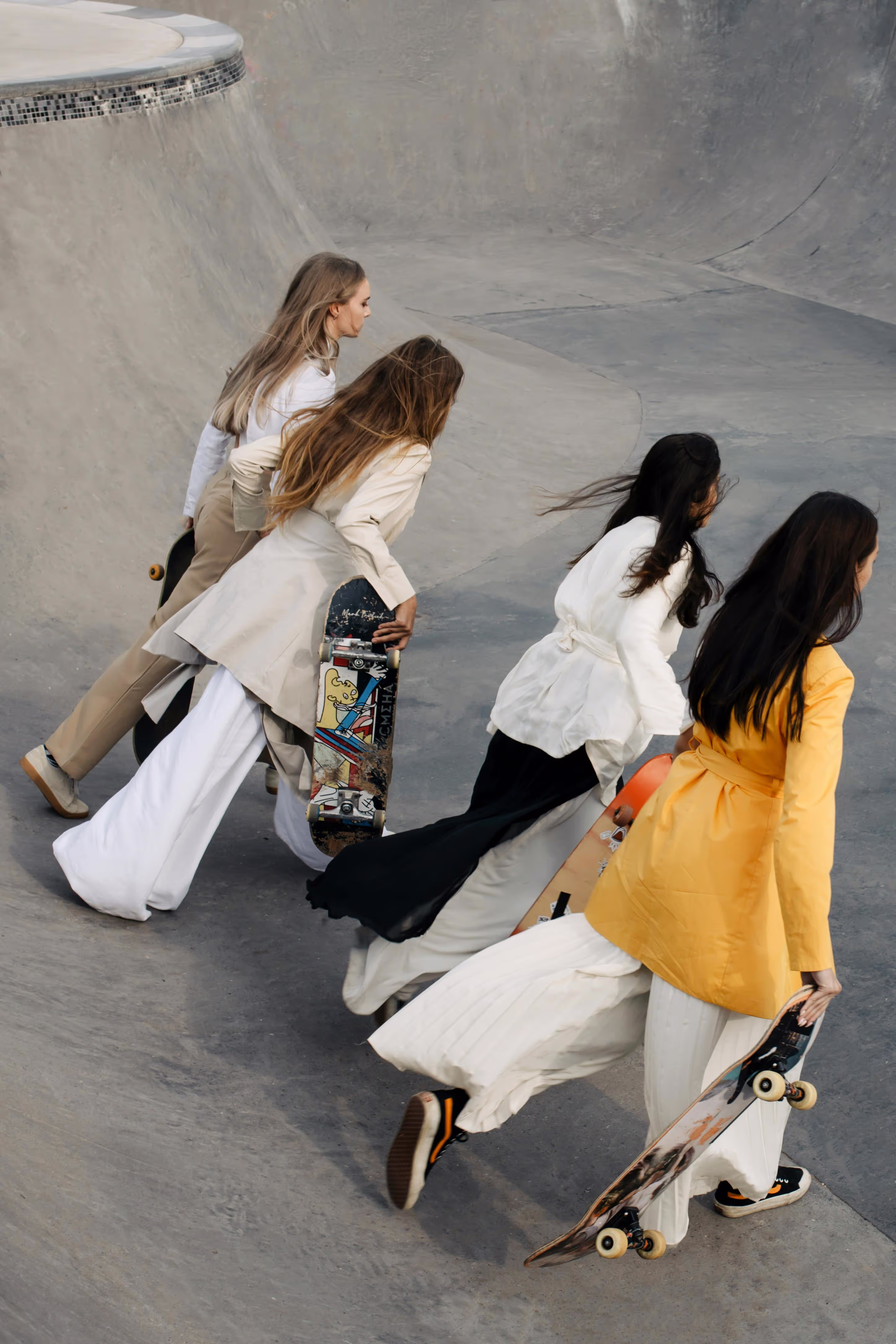 Four girls running with skateboards.