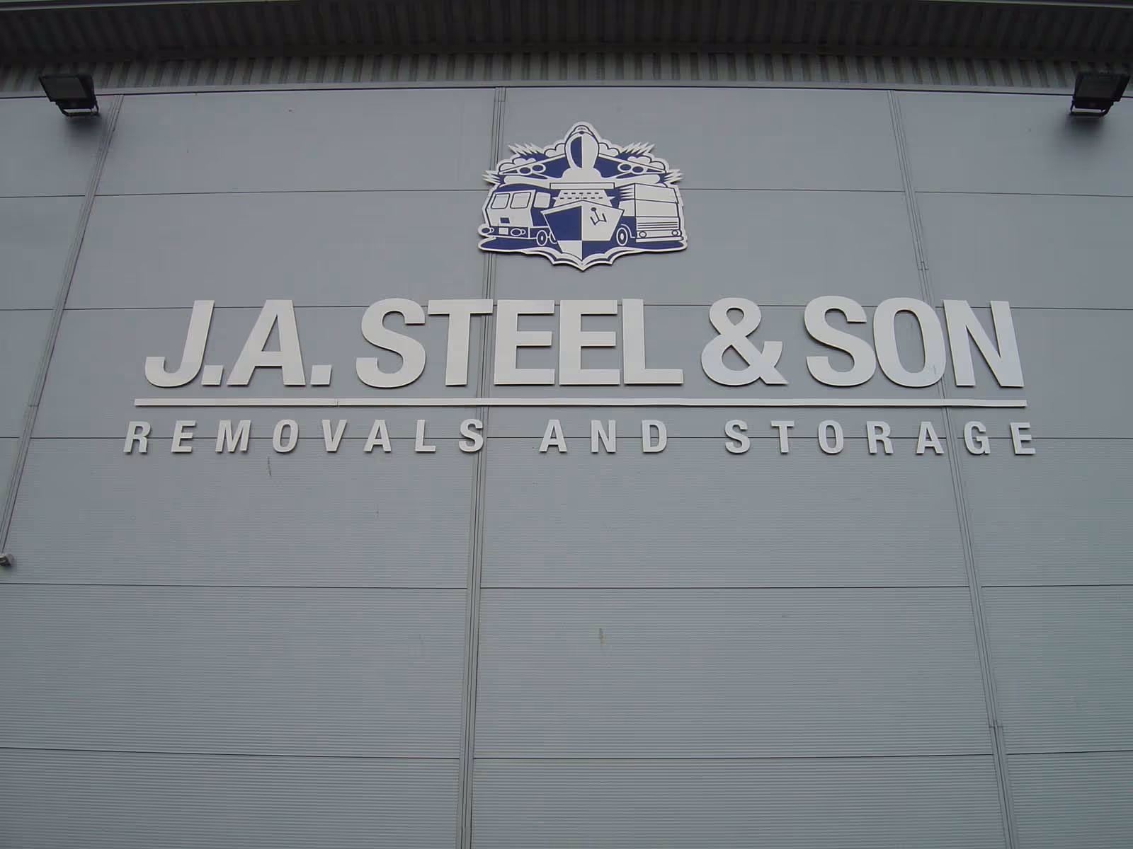 Sign reading "J.A. Steel & Son Removals and Storage" on building wall.