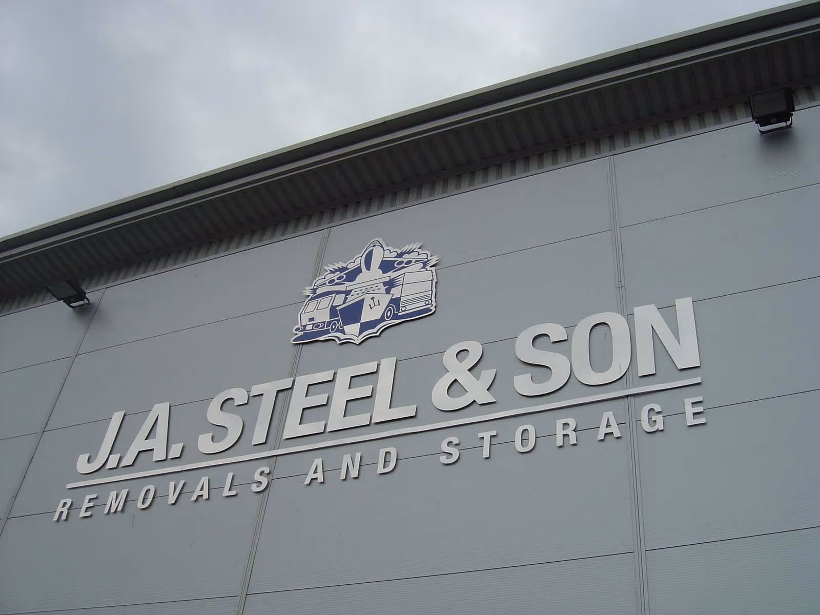 Sign on building reads "J.A. Steel & Son Removals and Storage" with moving truck logo.