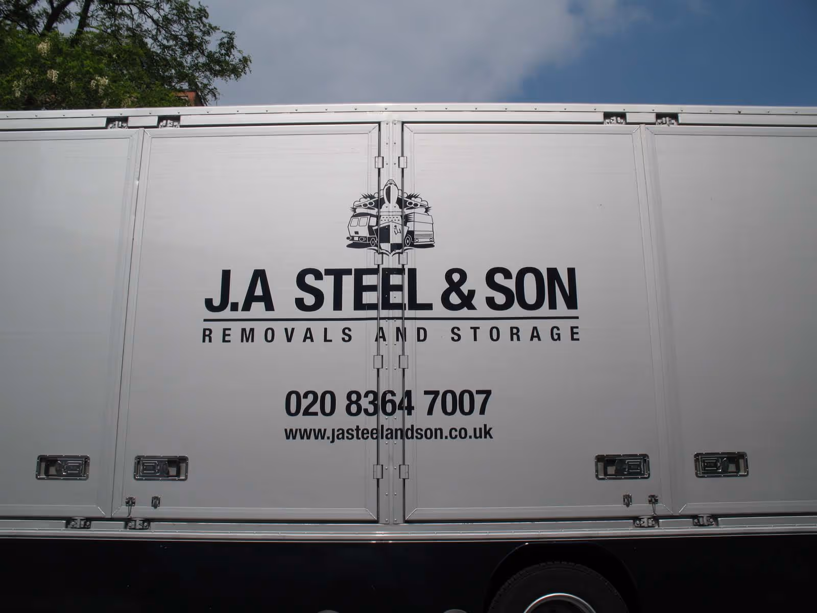 A white removal truck with "J.A Steel & Son Removals and Storage" and contact information on its side.