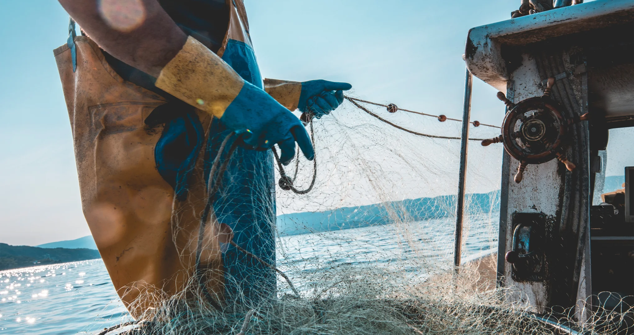 A fisherman on a boat pulling a net in.