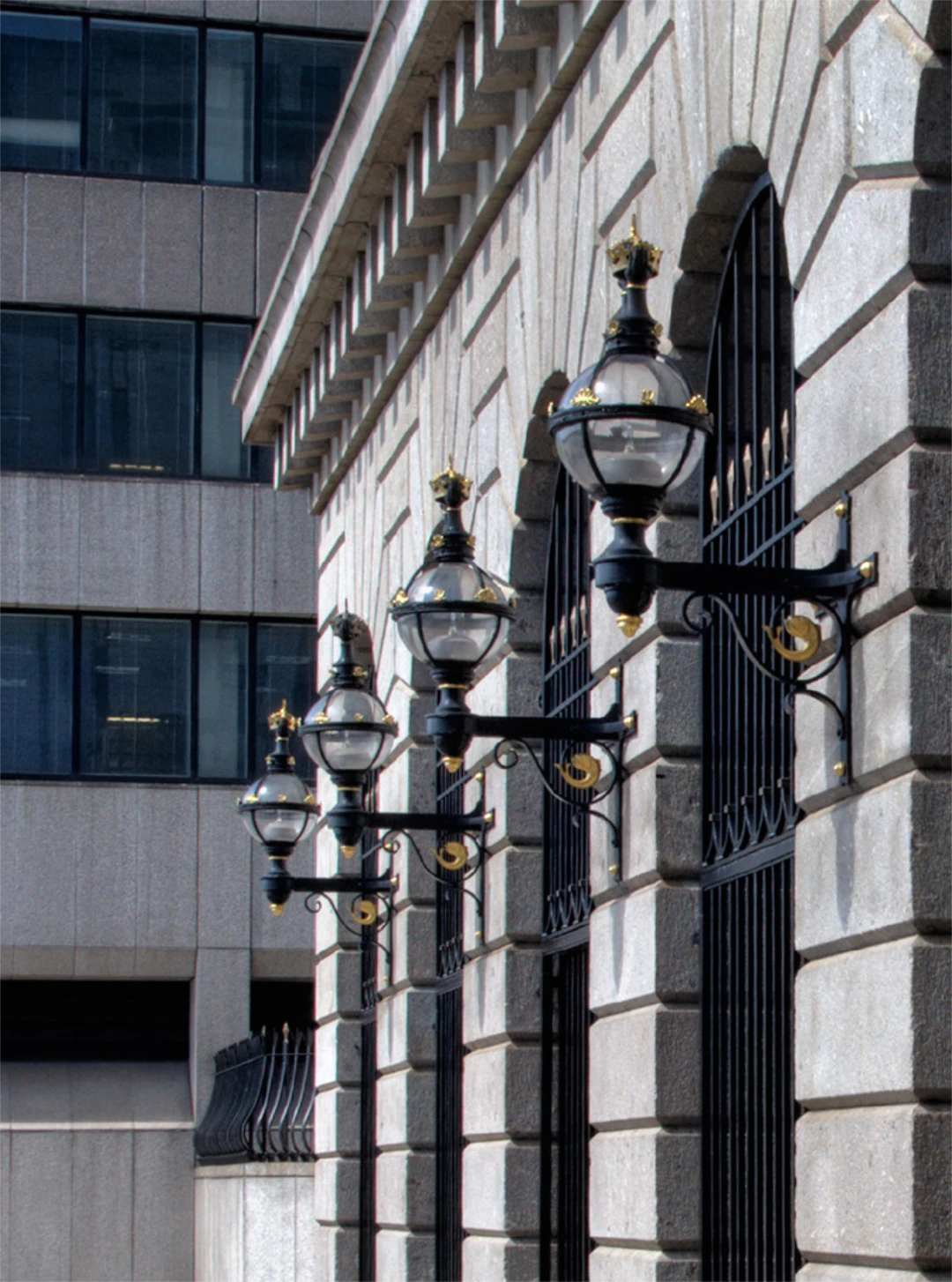 Wall in a city with lamp style lights in wrought iron.