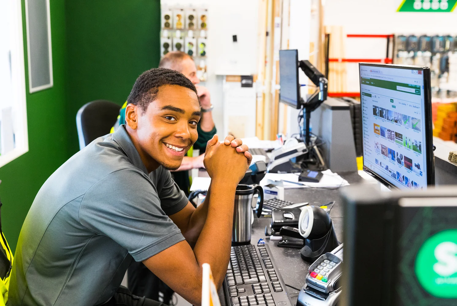 Happy young man smiling at his computer desk with the Chandlers builders merchant website on.
