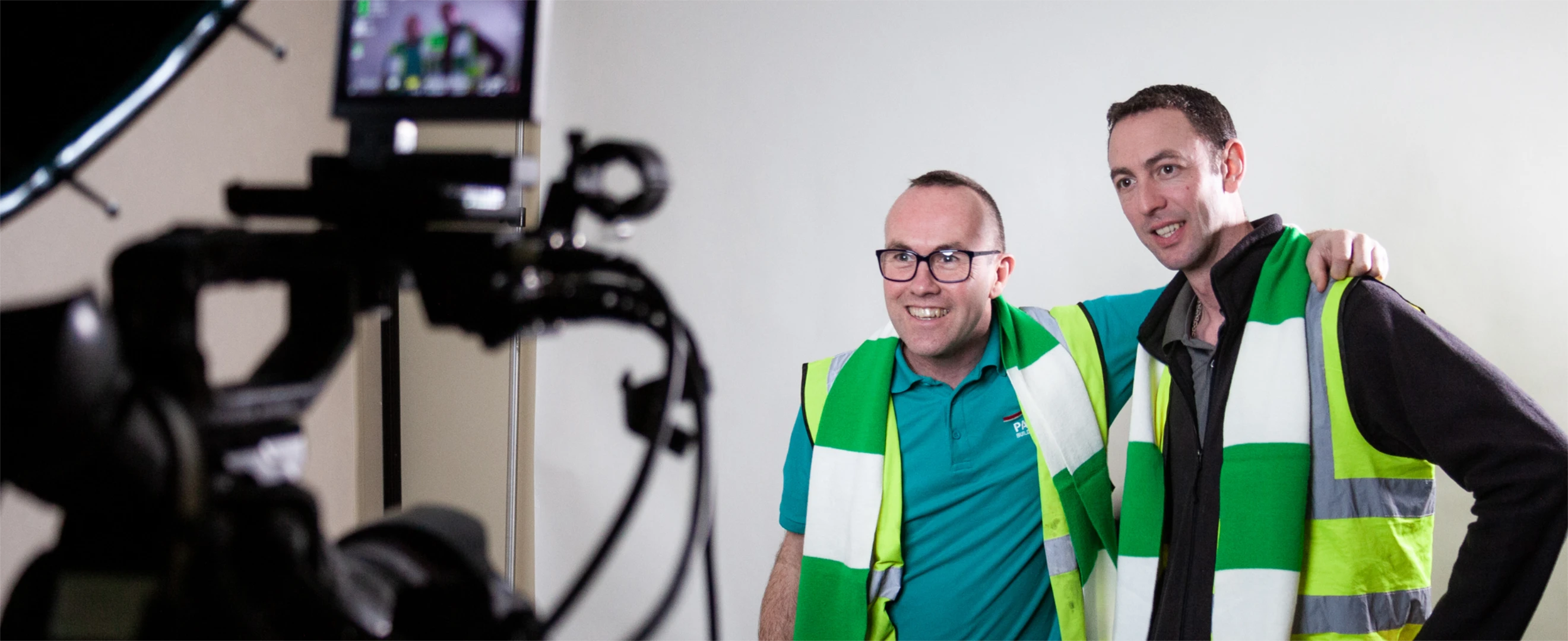 Two men in high visibility vests posing for a professional photograph and smiling.