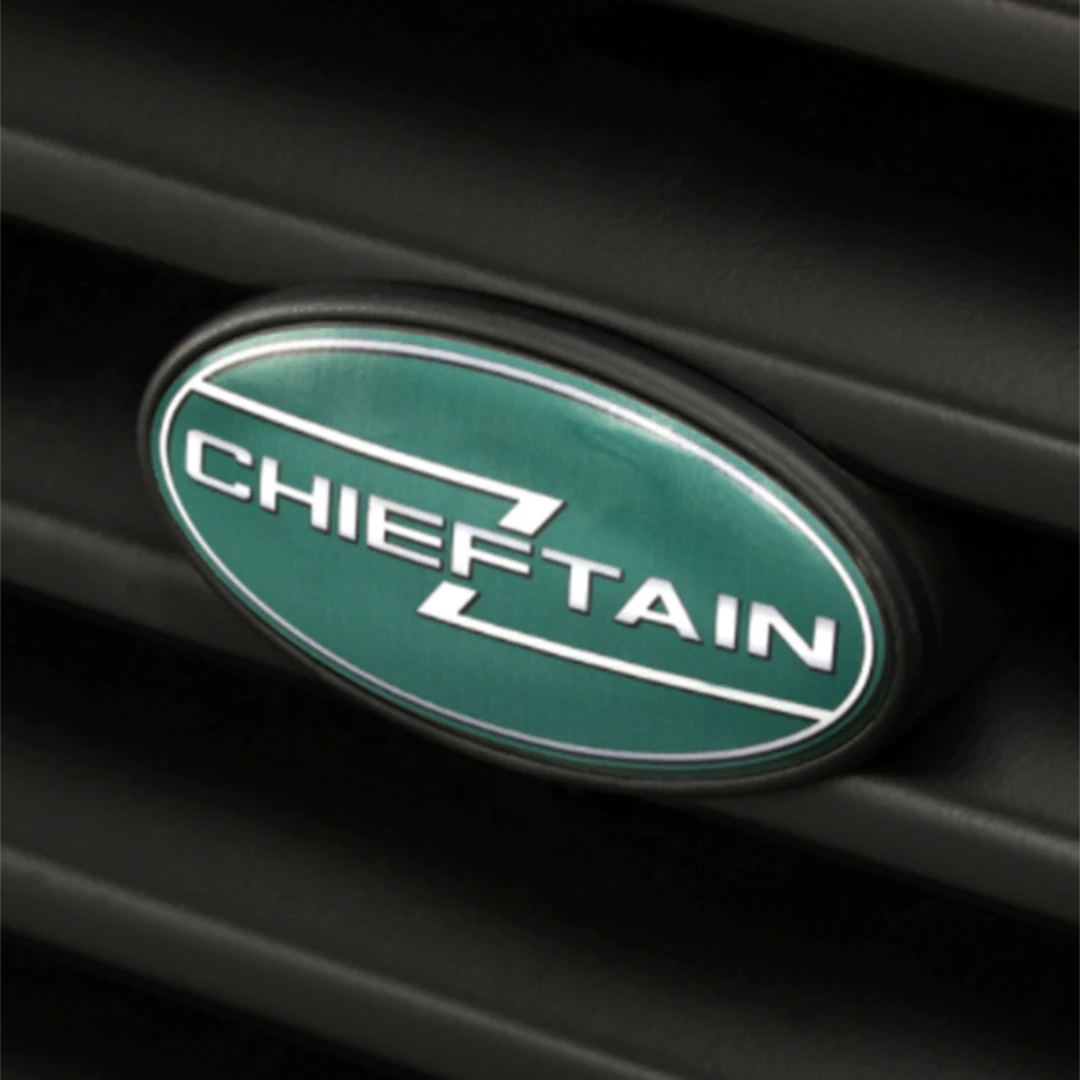 Green and white Cheiftain logo badge on the front grill of a car zoomed in.