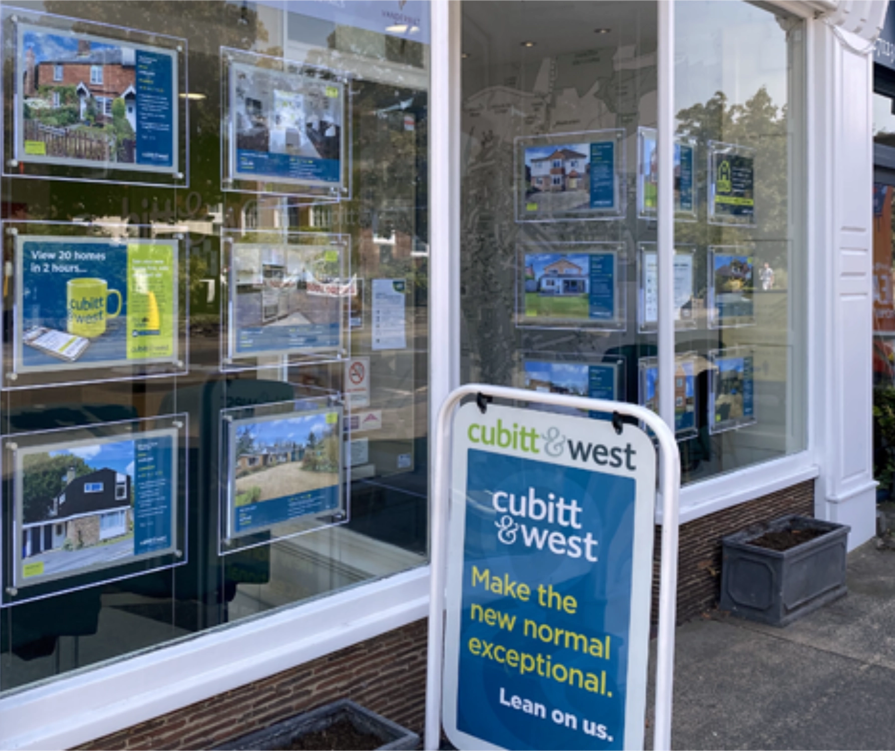 Window of an Arun Estates shop with a Cubitt & West swinging sign outside in blue, green and white.