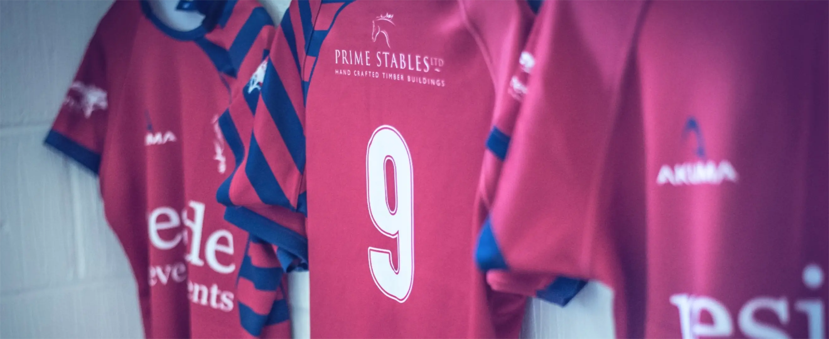 Three rugby kits in red, blue and white hanging in the changing room with a dramatic grey overlay.