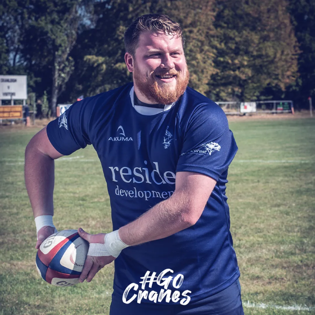 Rugby player from Cranleigh Rugby Club throwing a ball with a smile in blue kit.