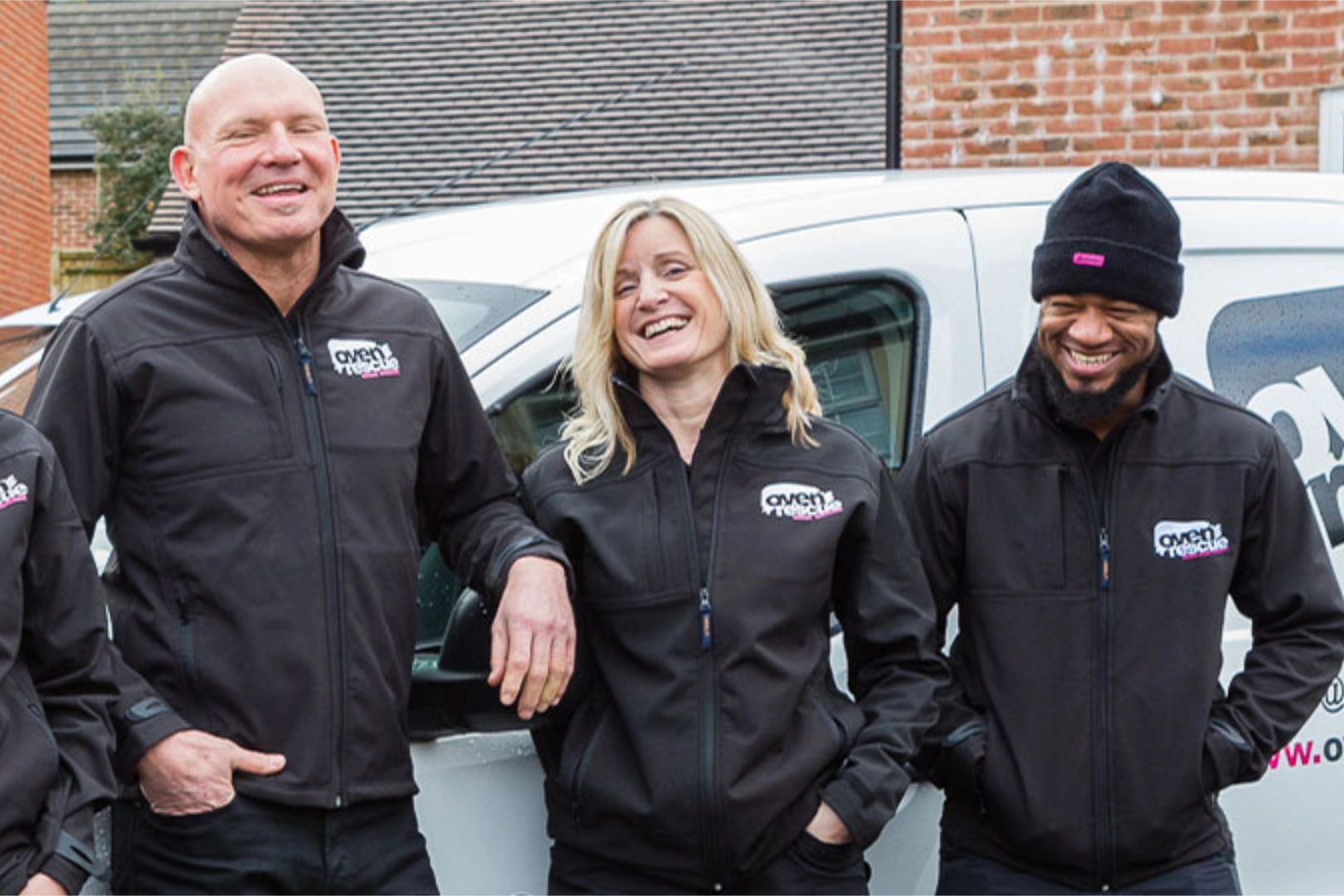 Happy Oven rescue team in black uniforms standing outside their van.