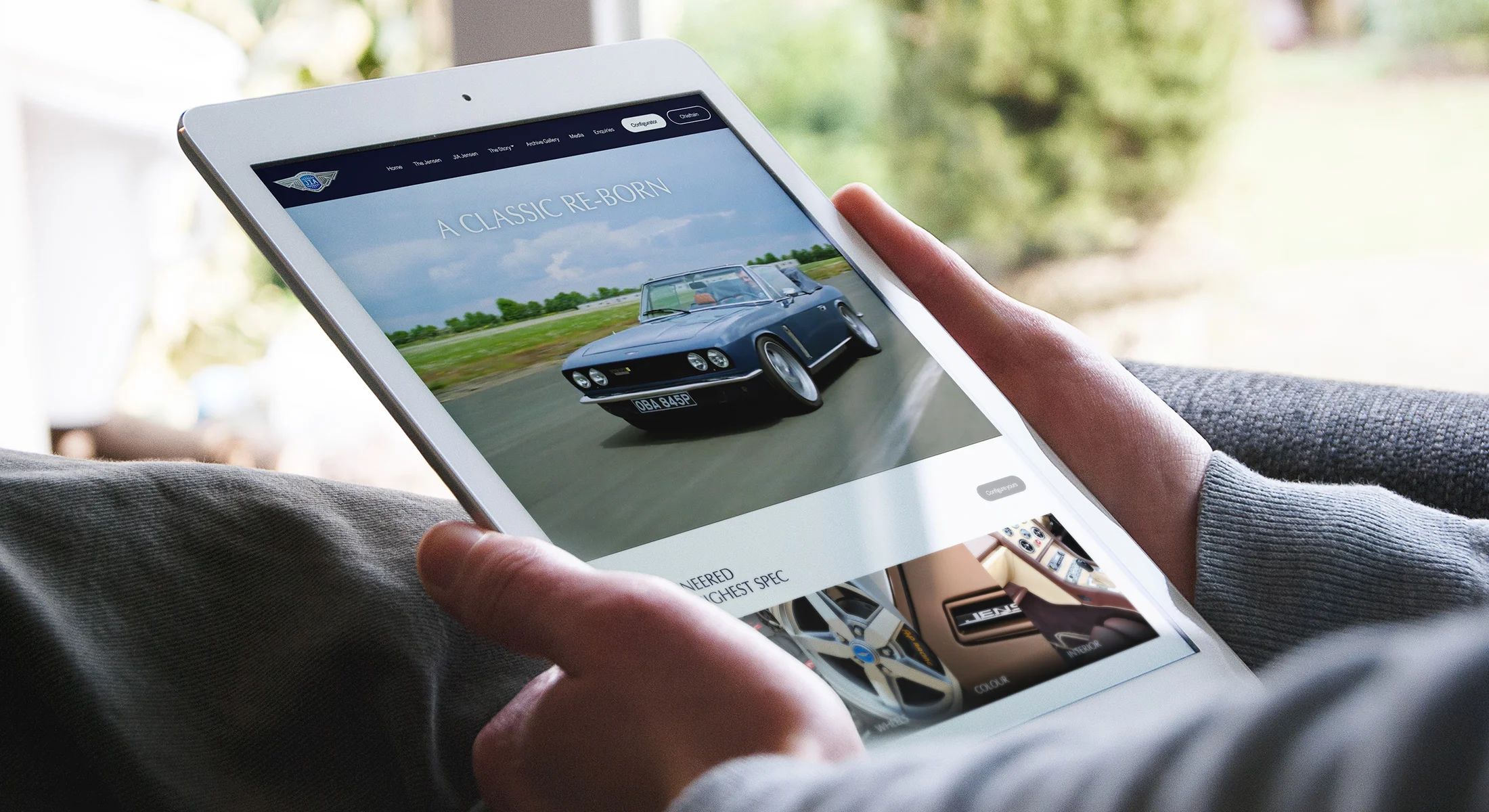 Person using Jensen International Automotive website on a tablet showcasing its responsive website design.