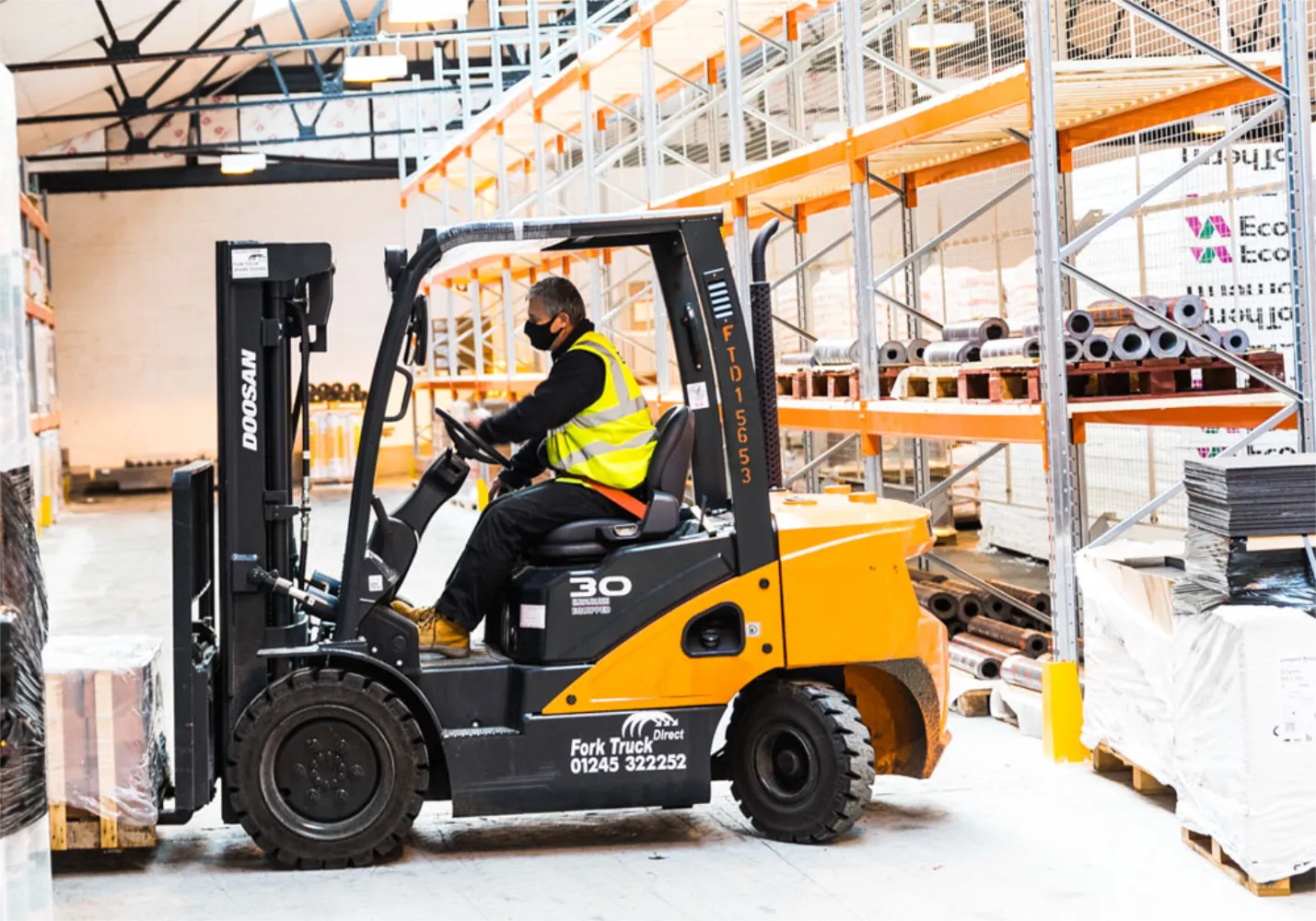 Man driving a counterbalance forklift inside a builders warehouse.
