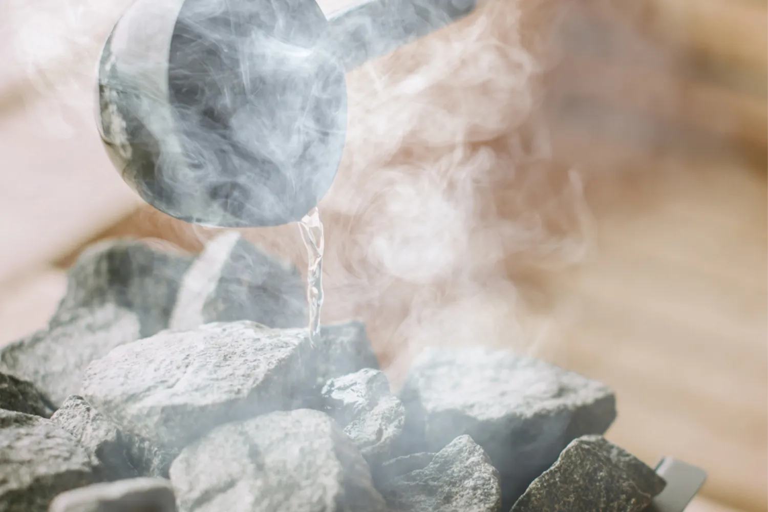 Water being poured over hot coals in a steam room.