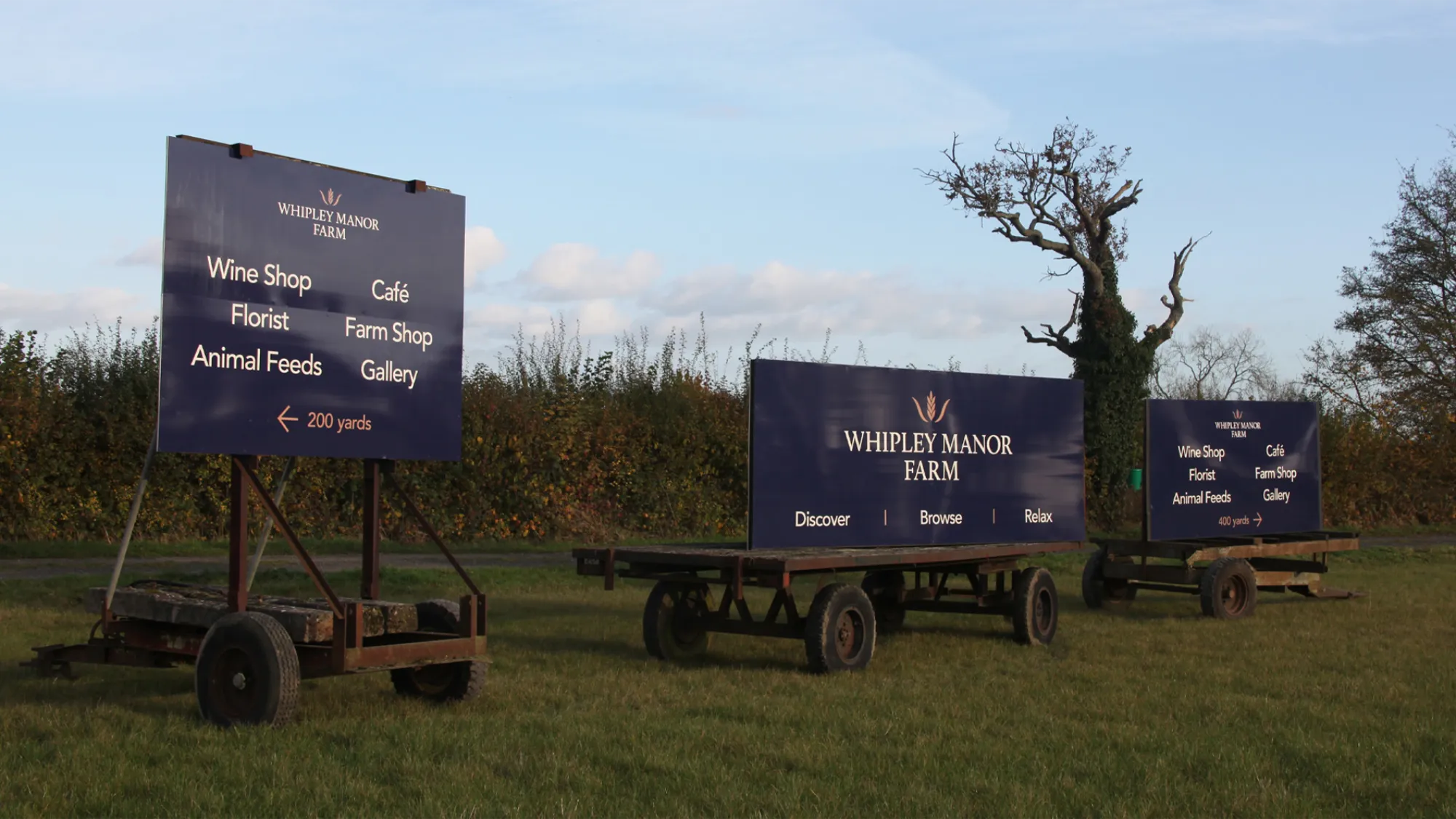 Whipley Manor Farm signage on different types of trailers within the farm.