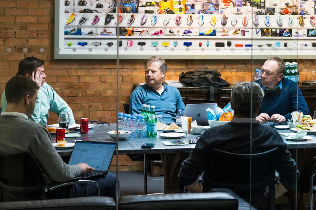 People sitting at a conference table talking business all dressed business casual in a red brick room.
