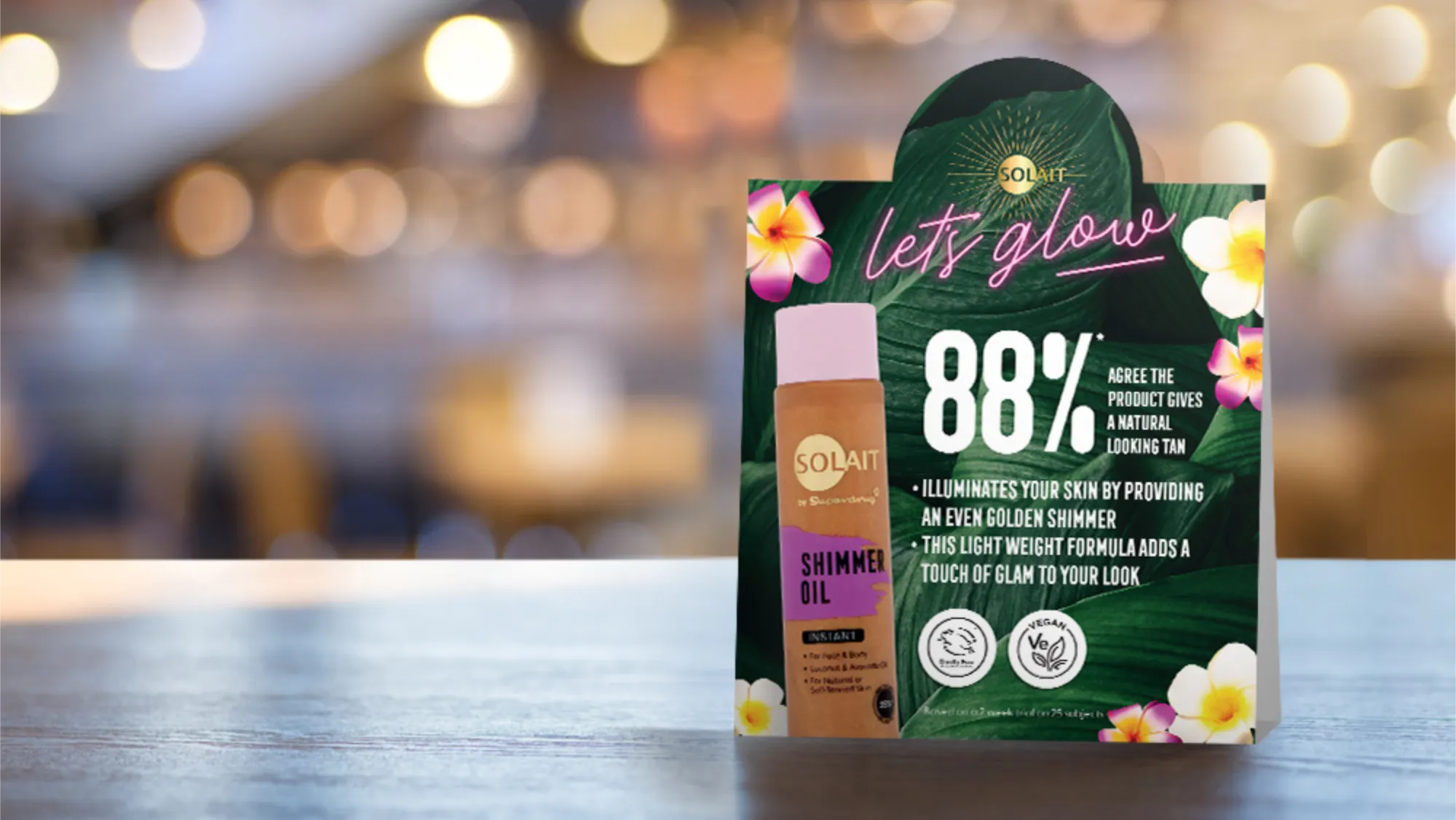 Table tent card advertising Solait Shimmer Oil with 88% agreeing it gives a natural looking tan, highlighting even golden shimmer and lightweight formula benefits.