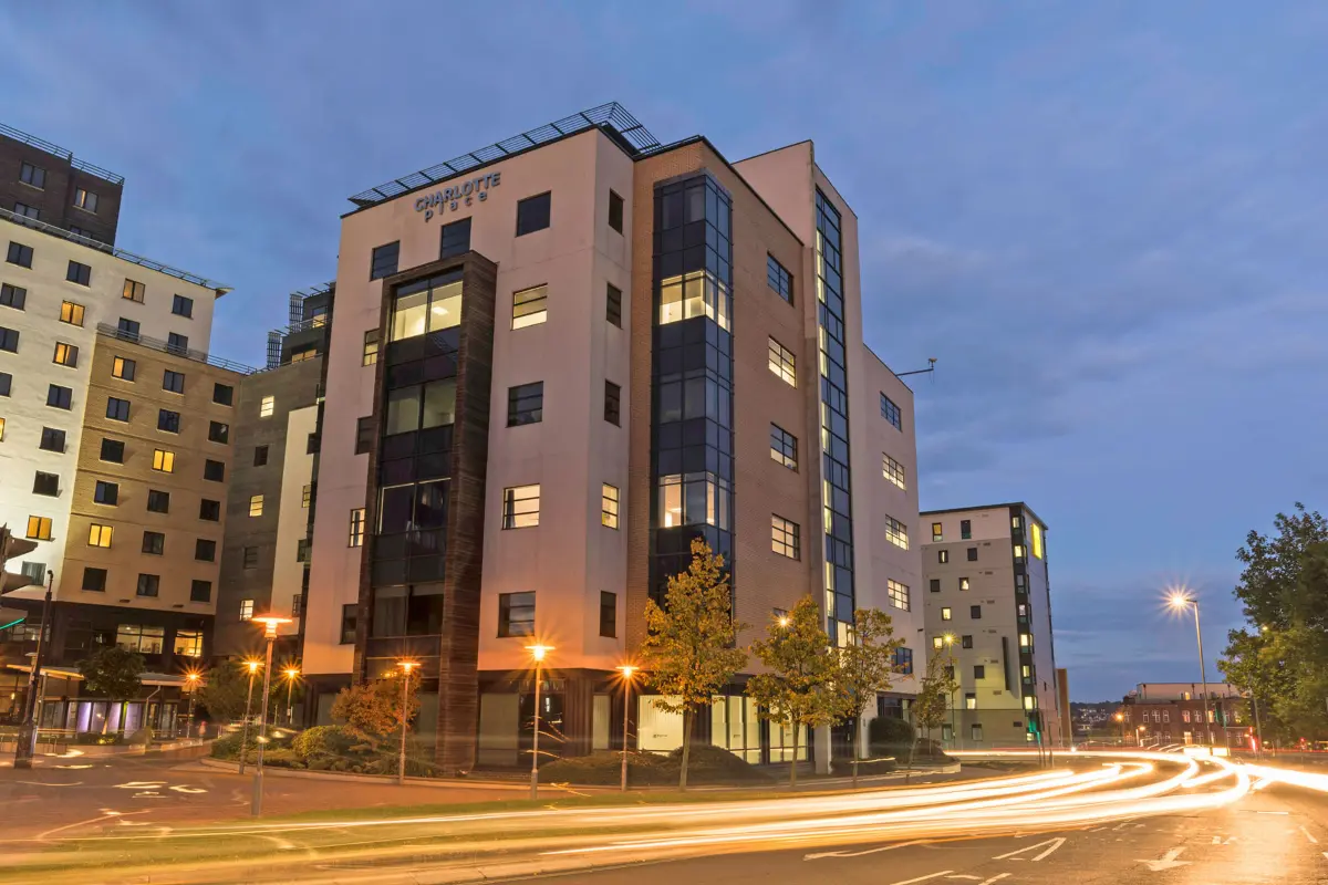 Charlotte Place building at dusk with light trails from cars on the street in front.