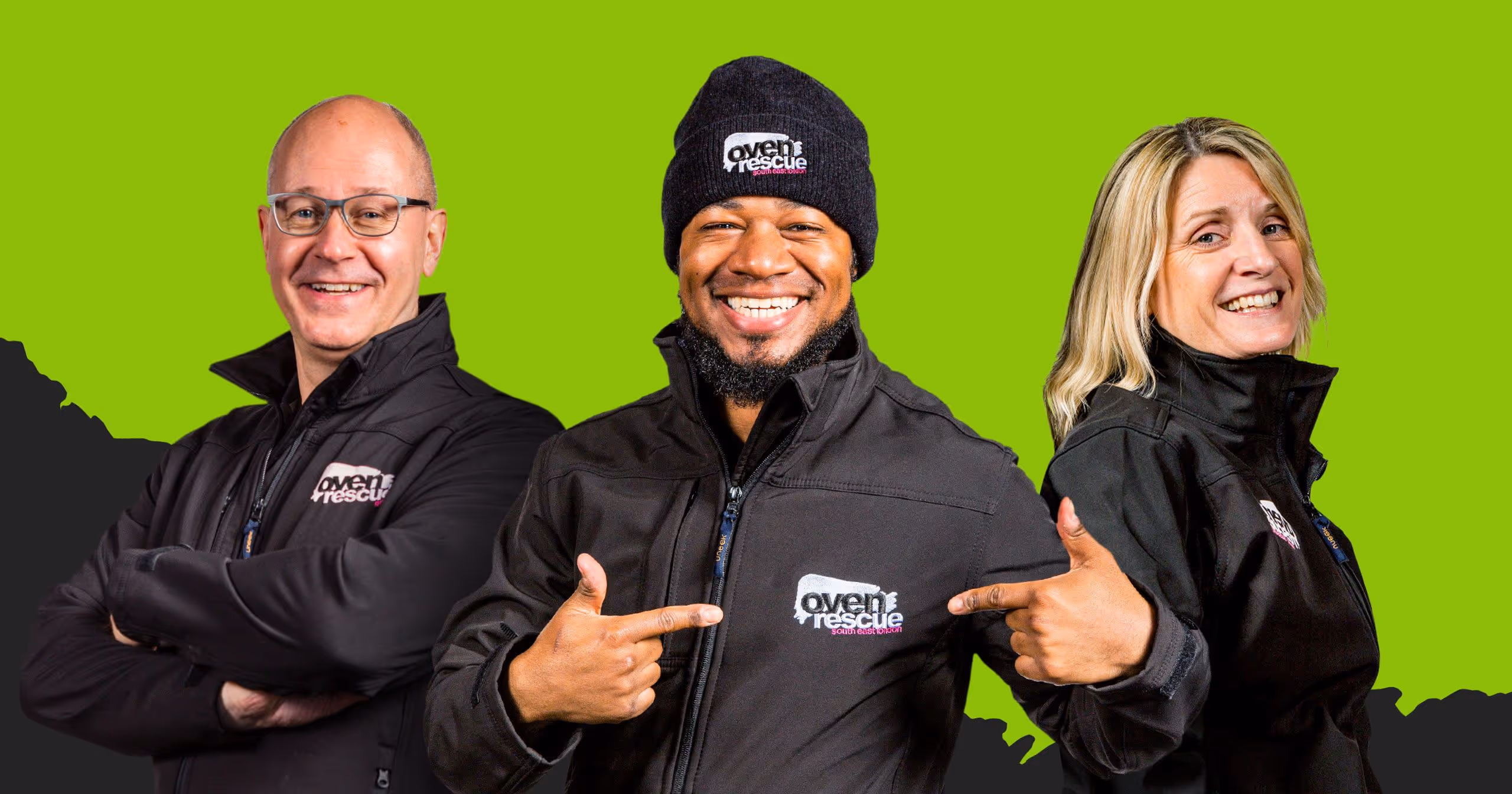 Three smiling Oven Rescue workers wearing black jackets, with the middle person pointing at the company logo on his jacket.