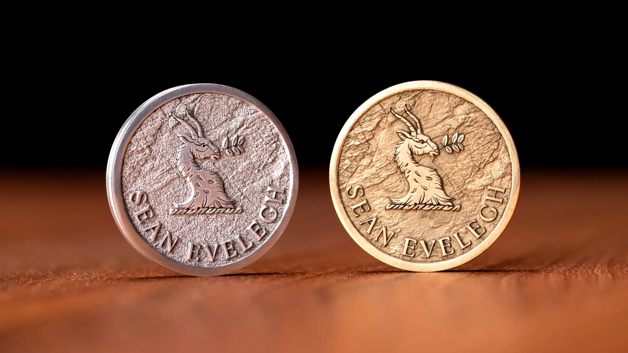 Sean Evelegh logo on a gold and silver coin standing up on a table.