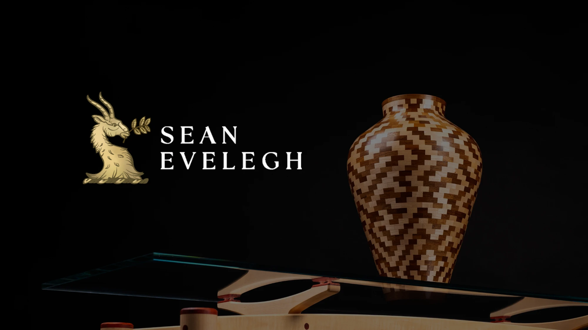 Sean Evelegh logo in gold and white on a dark background with an ornate pot on a glass table.