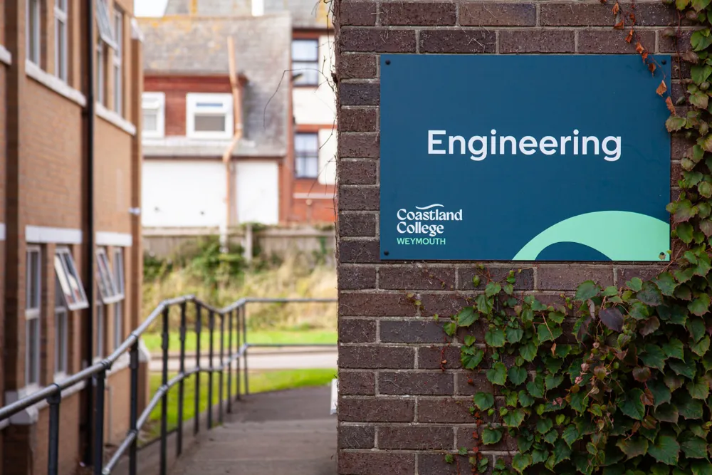 A sign in Coastland College that reads "ENGINEERING" in blue and green with a large green swoosh.
