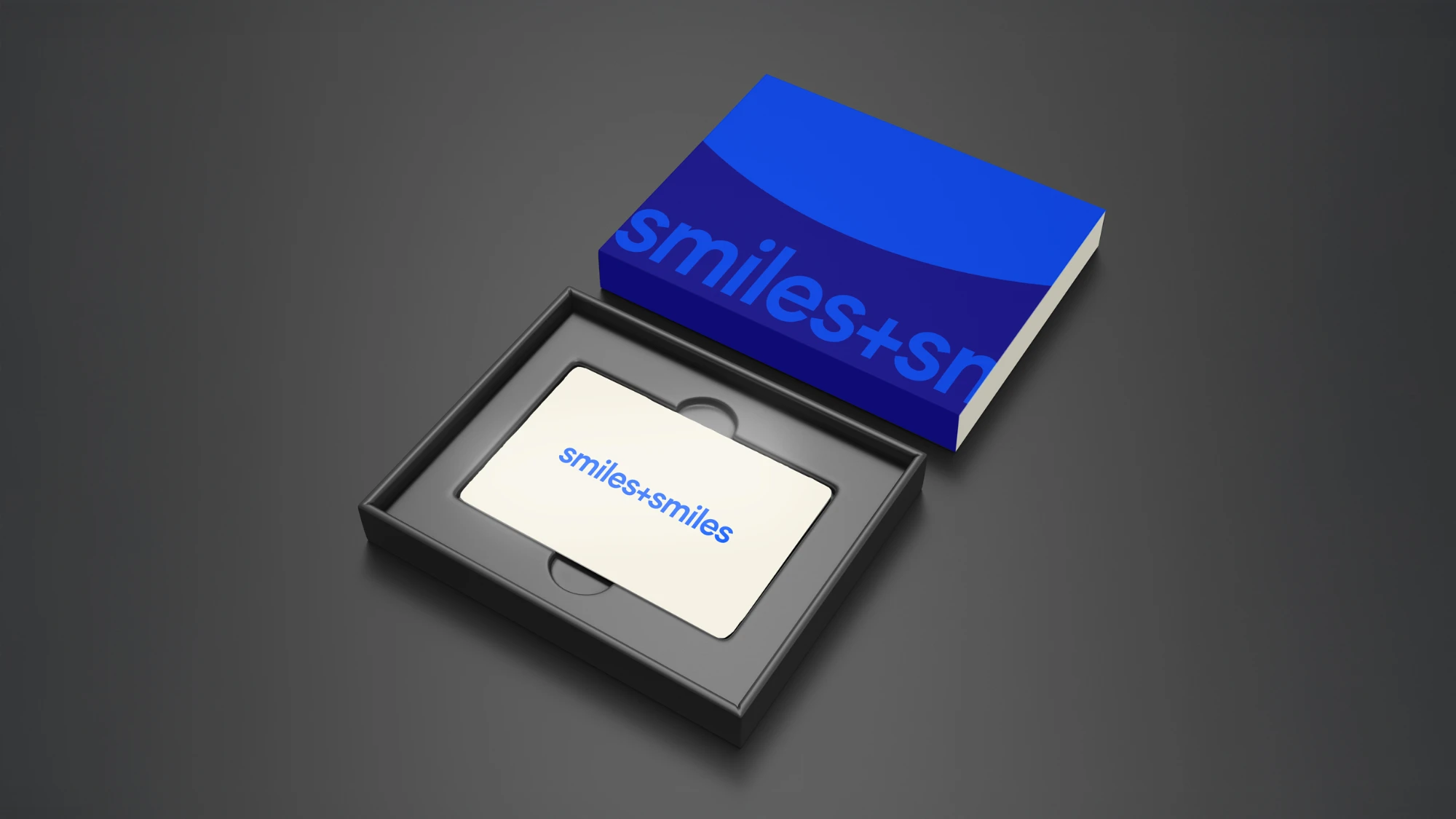 Open black box with a white gift card inside that reads 'smiles+smiles' and a blue card sleeve with partial text 'smiles+sm'.